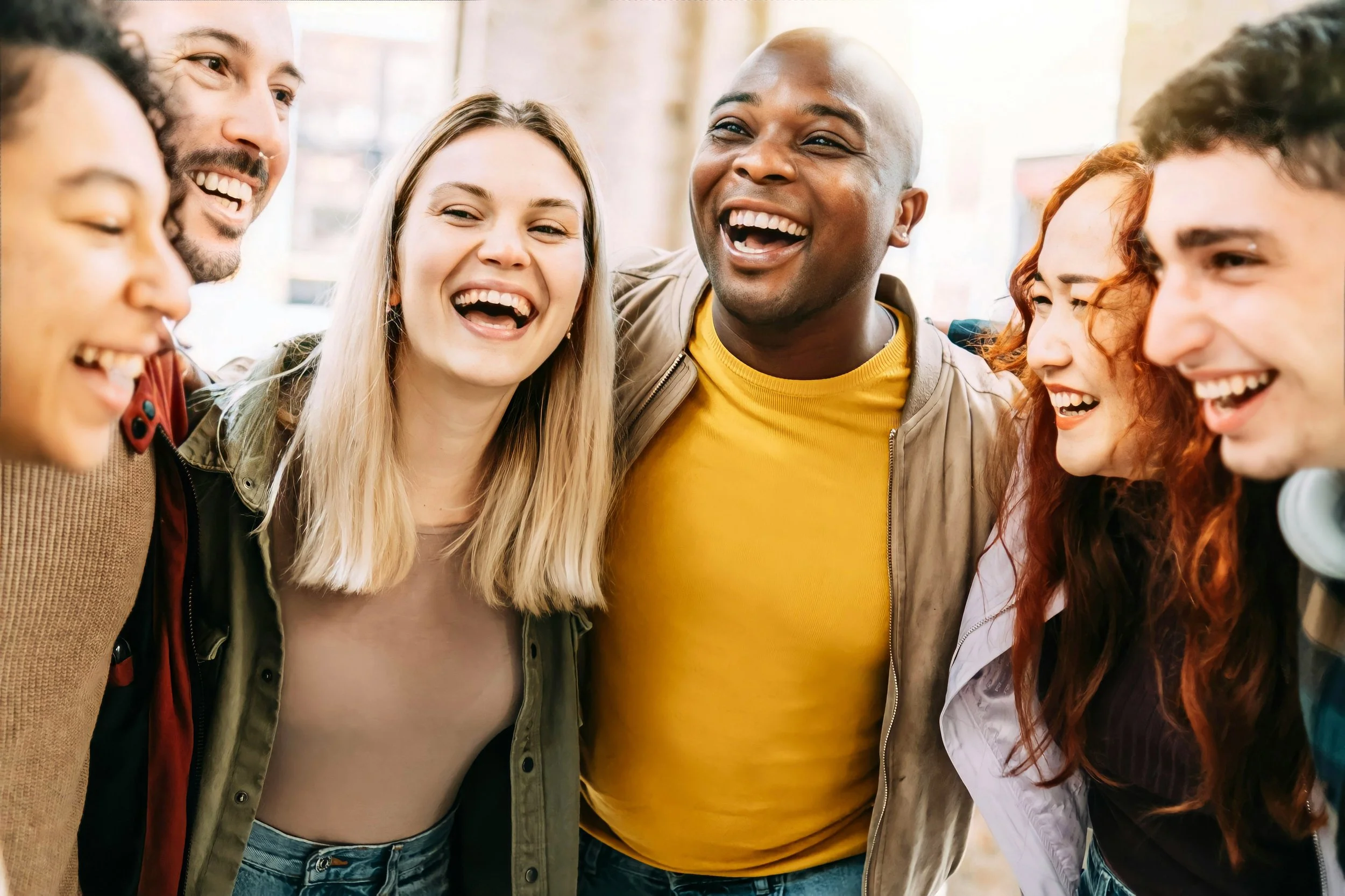 Group of diverse young adults smiling and laughing together indoors.