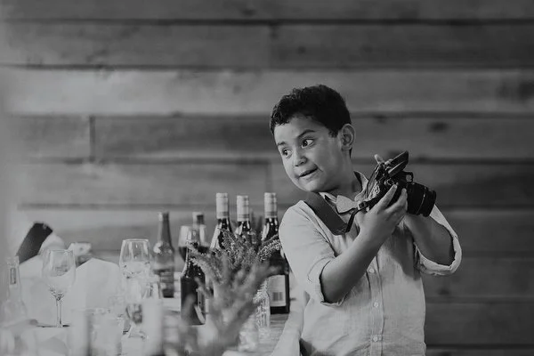 Black and white image of young boy as he gets his first taste for photography and is excited to show off his great photo.