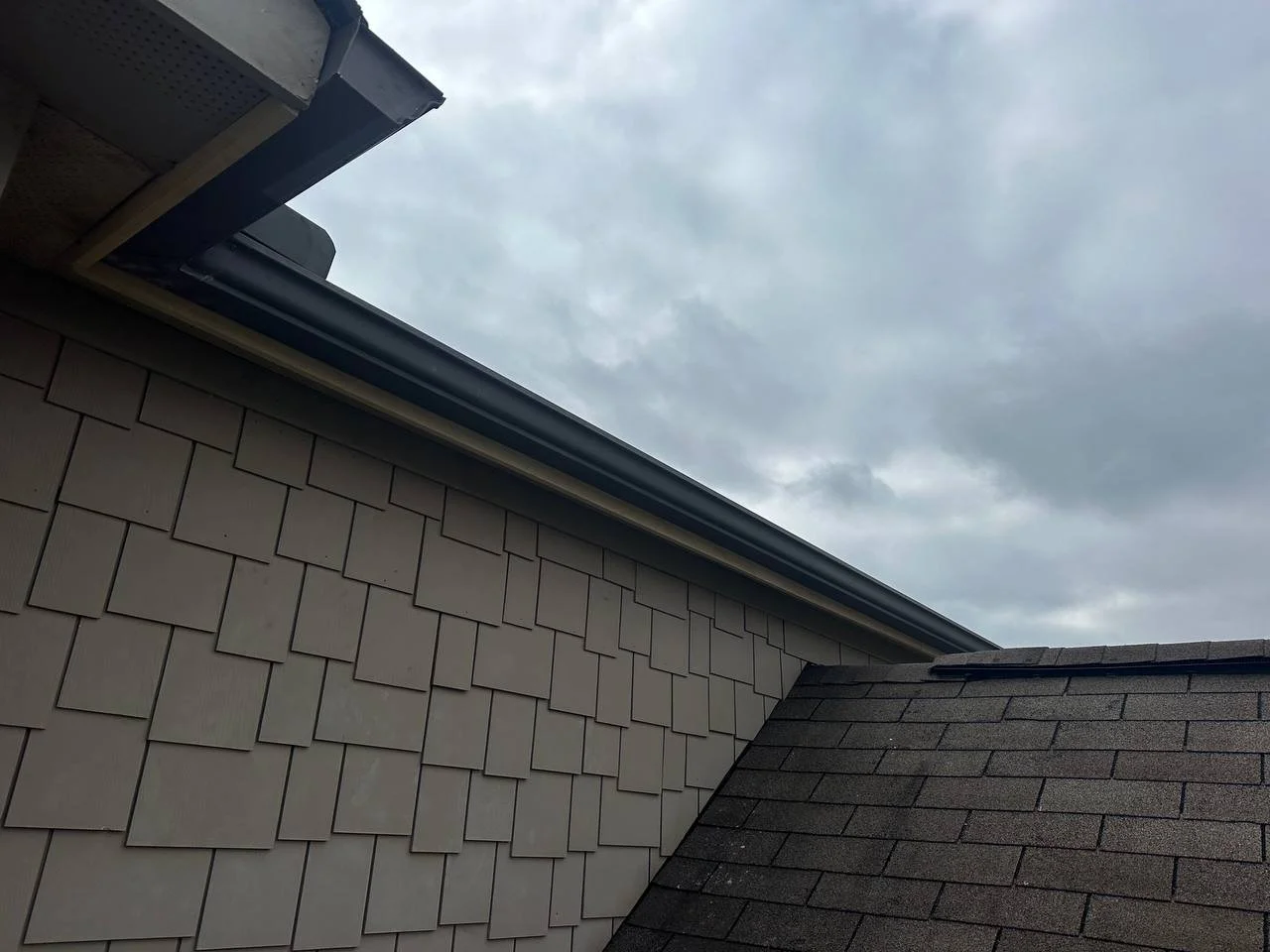 Close-up of house roof and siding with cloudy sky overhead
