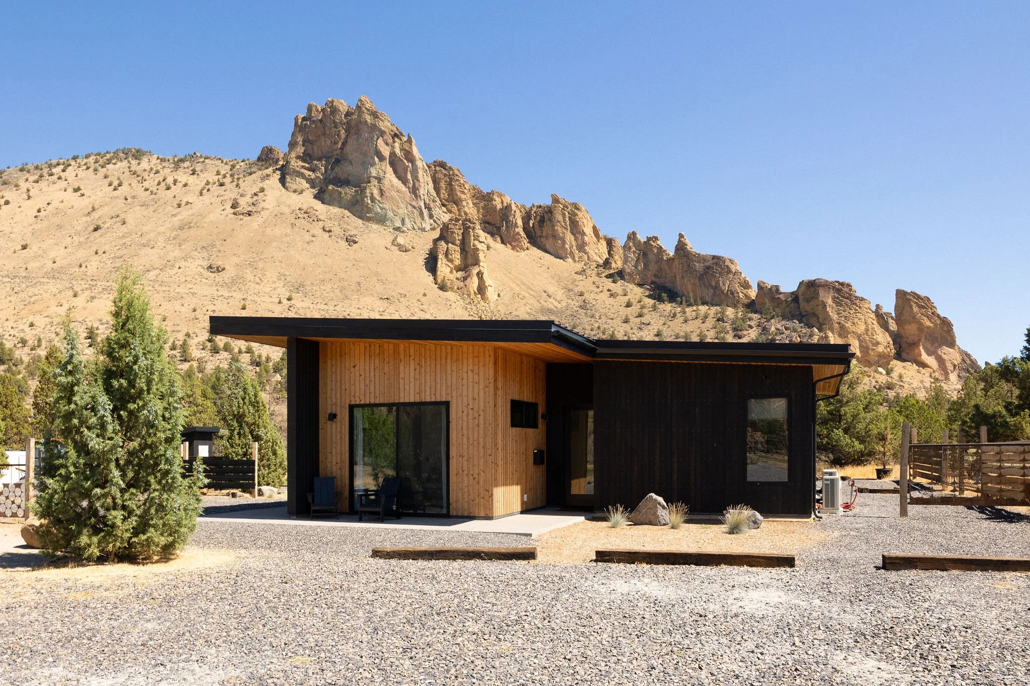 Modern house with wood and black exterior, set against a mountainous landscape during daytime