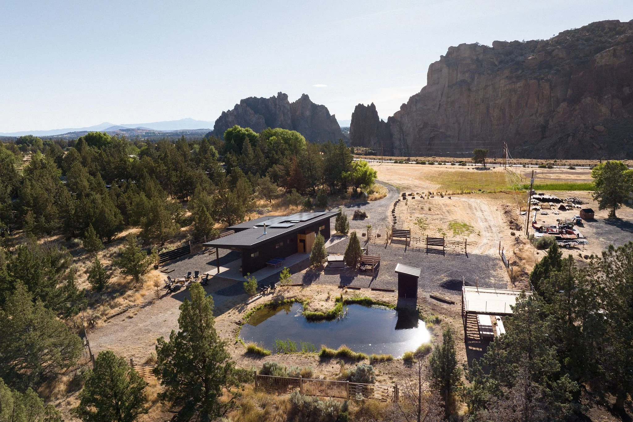 A modern Scandinavian-styled residence with a small pond, entertaining area backdropped by Smith Rock State Park.