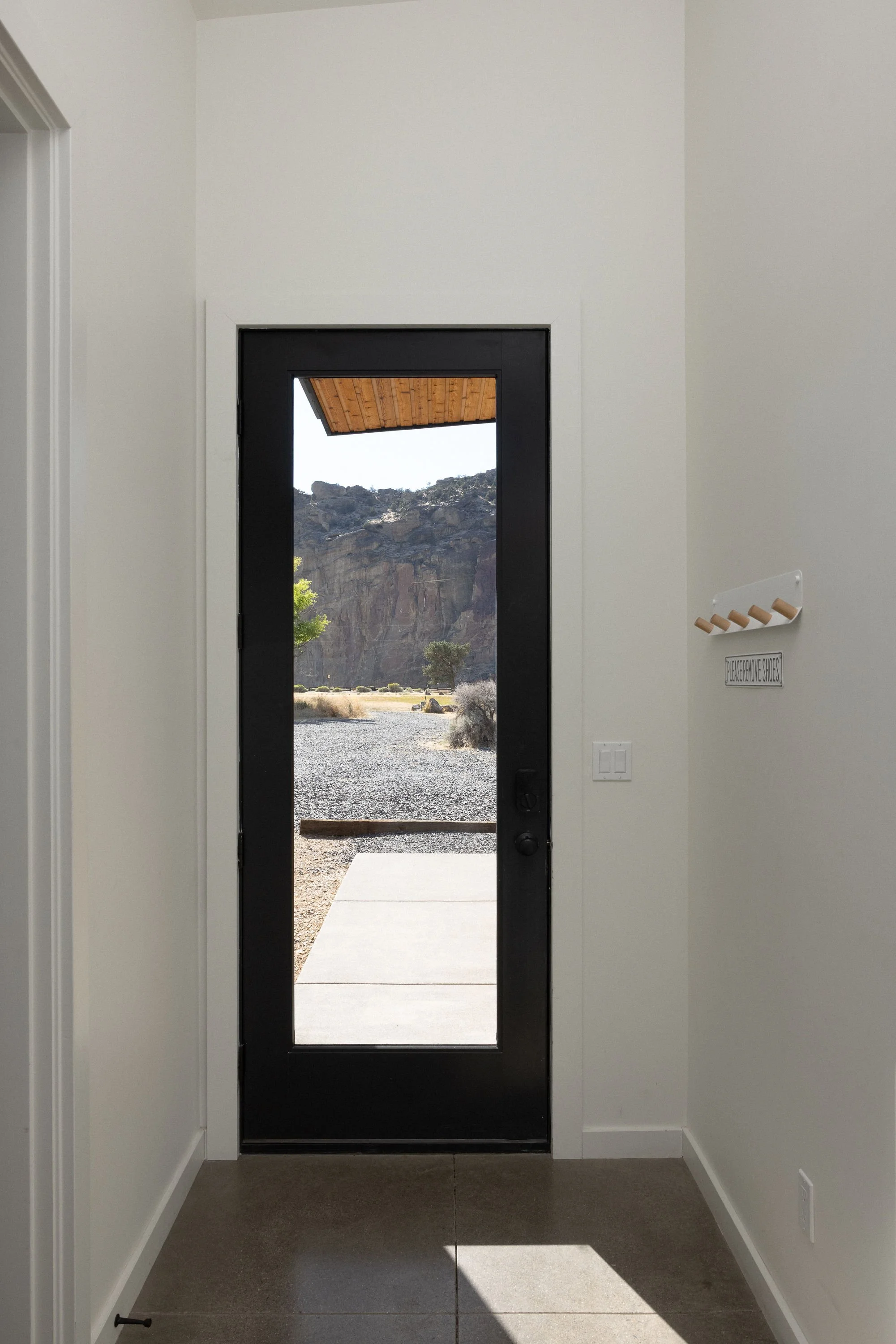 Interior view of a modern entryway with a black door leading outside to a landscape with rocks and cliffs.