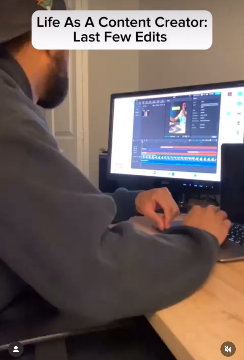 Person working on video editing on a computer at a desk with a monitor displaying editing software and a photo or video thumbnail. Text overlay reads 'Life As A Content Creator: Last Few Edits'.