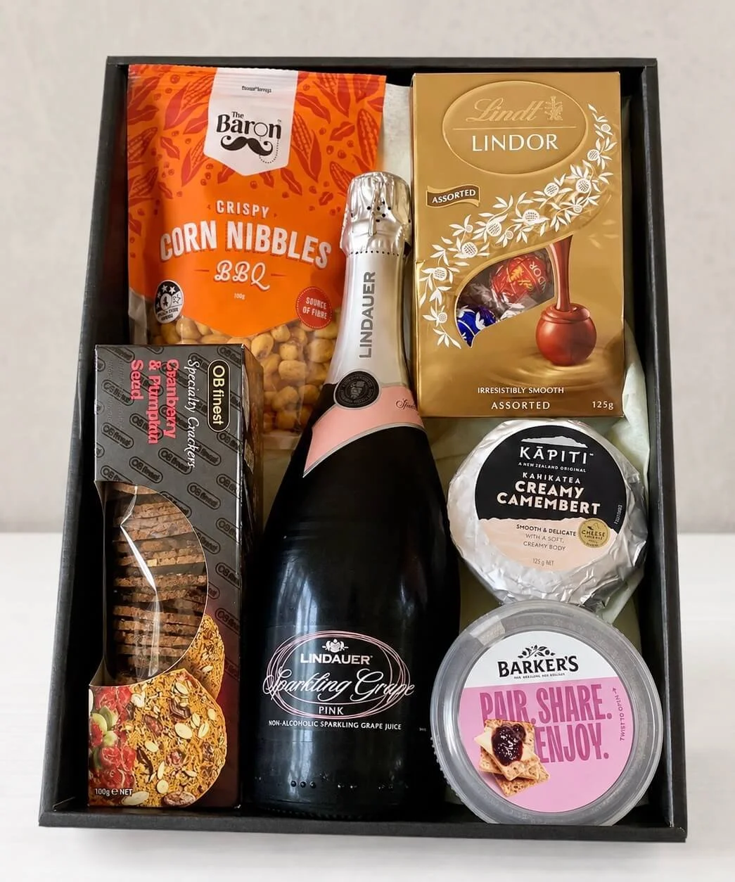 gift tray sitting upright with sparkling grape juice, chocolates, crackers, corn nibbles, cheese and a dip, levin delivery.