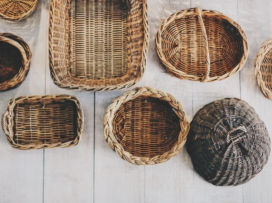 Collection of woven wicker baskets of various shapes and sizes on a wooden surface.