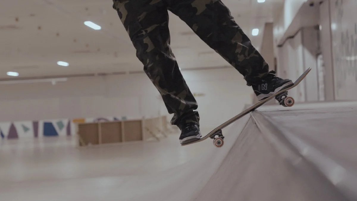 A person skateboarding inside a skatepark, performing a trick on the edge of a ramp, wearing camouflage pants and black sneakers.