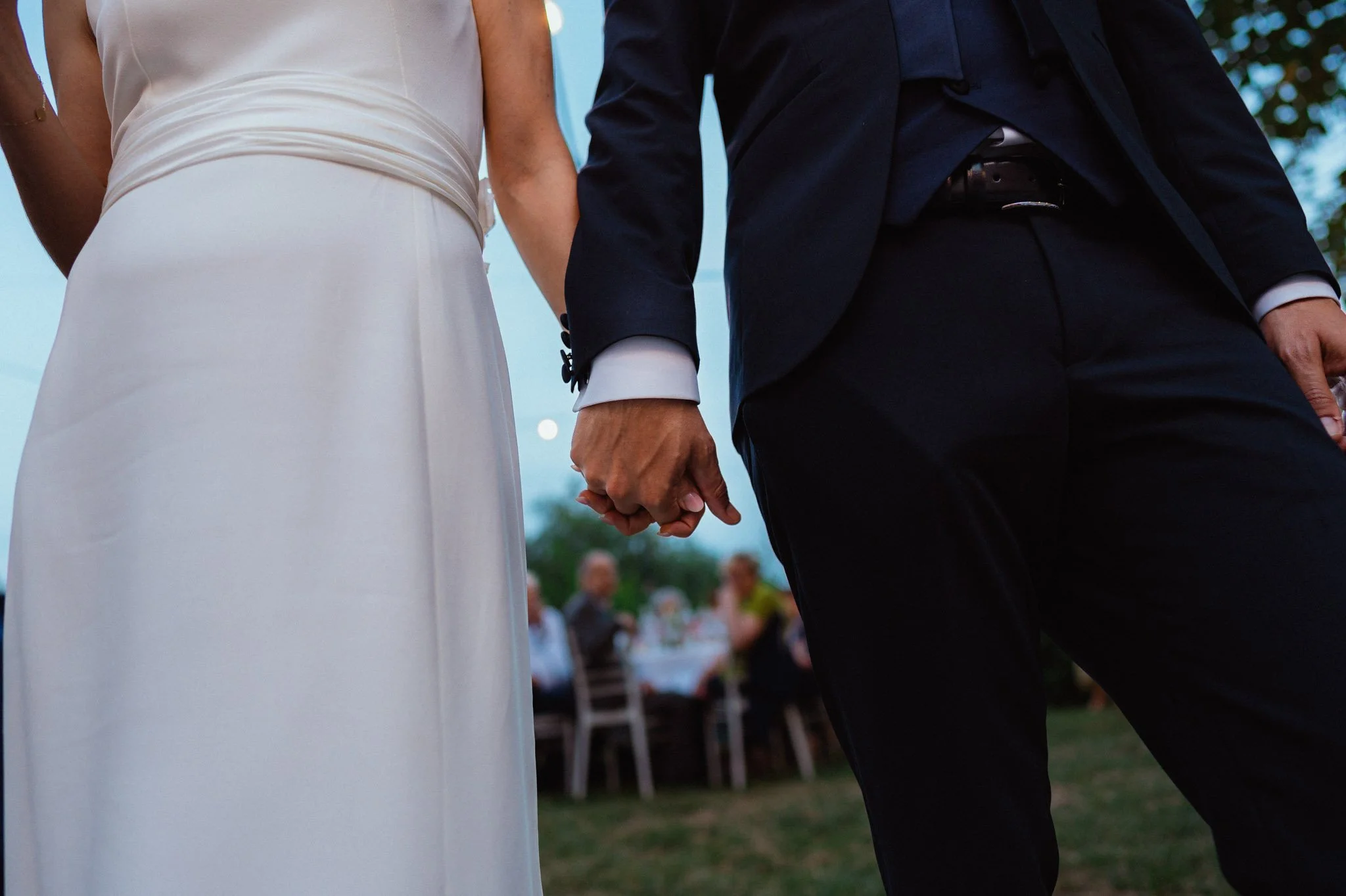 Coppia di sposi che si tengono per mano durante un matrimonio all'aperto