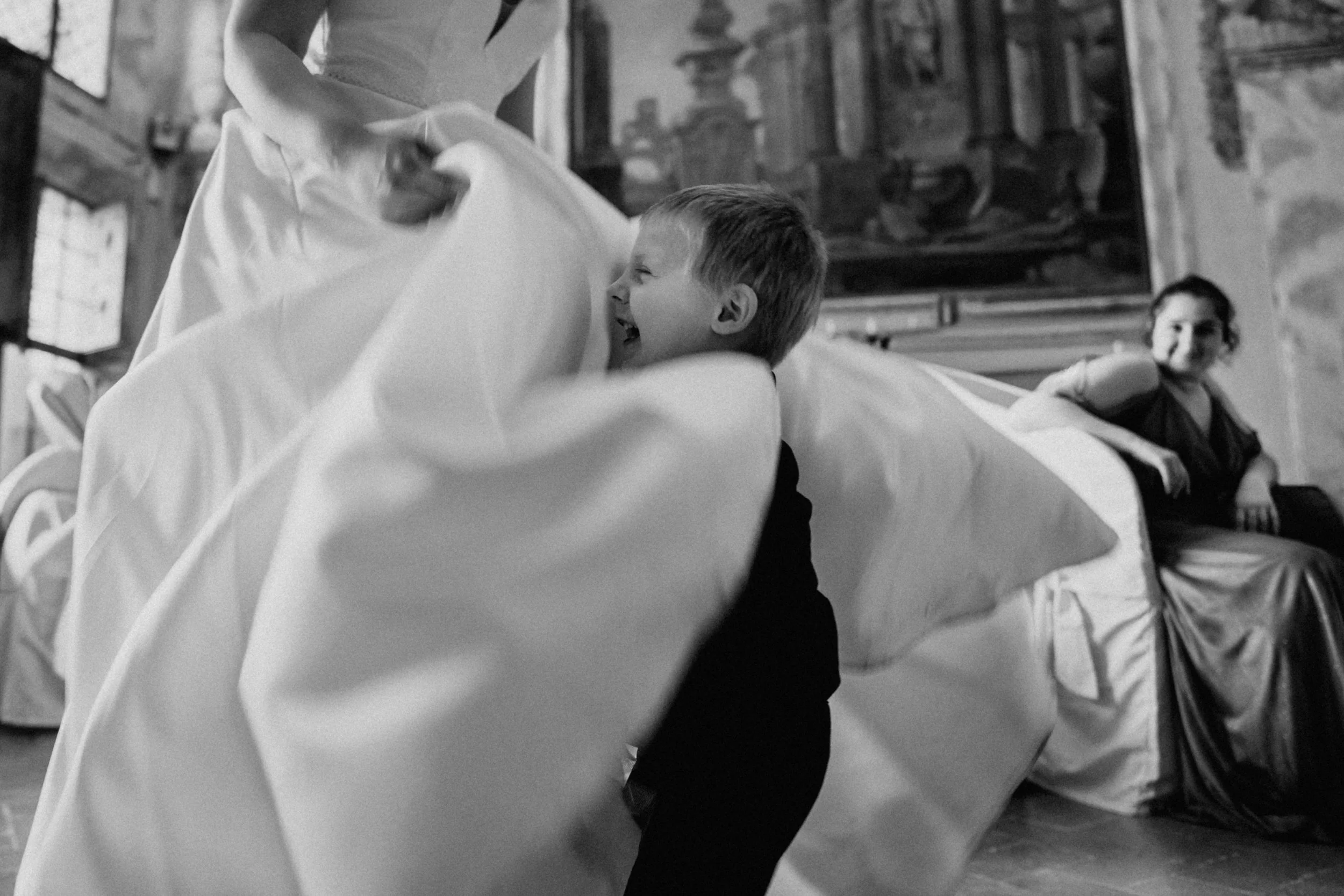 Un bambino ride mentre gioca corre verso il vestito della sposa in un locale storico.