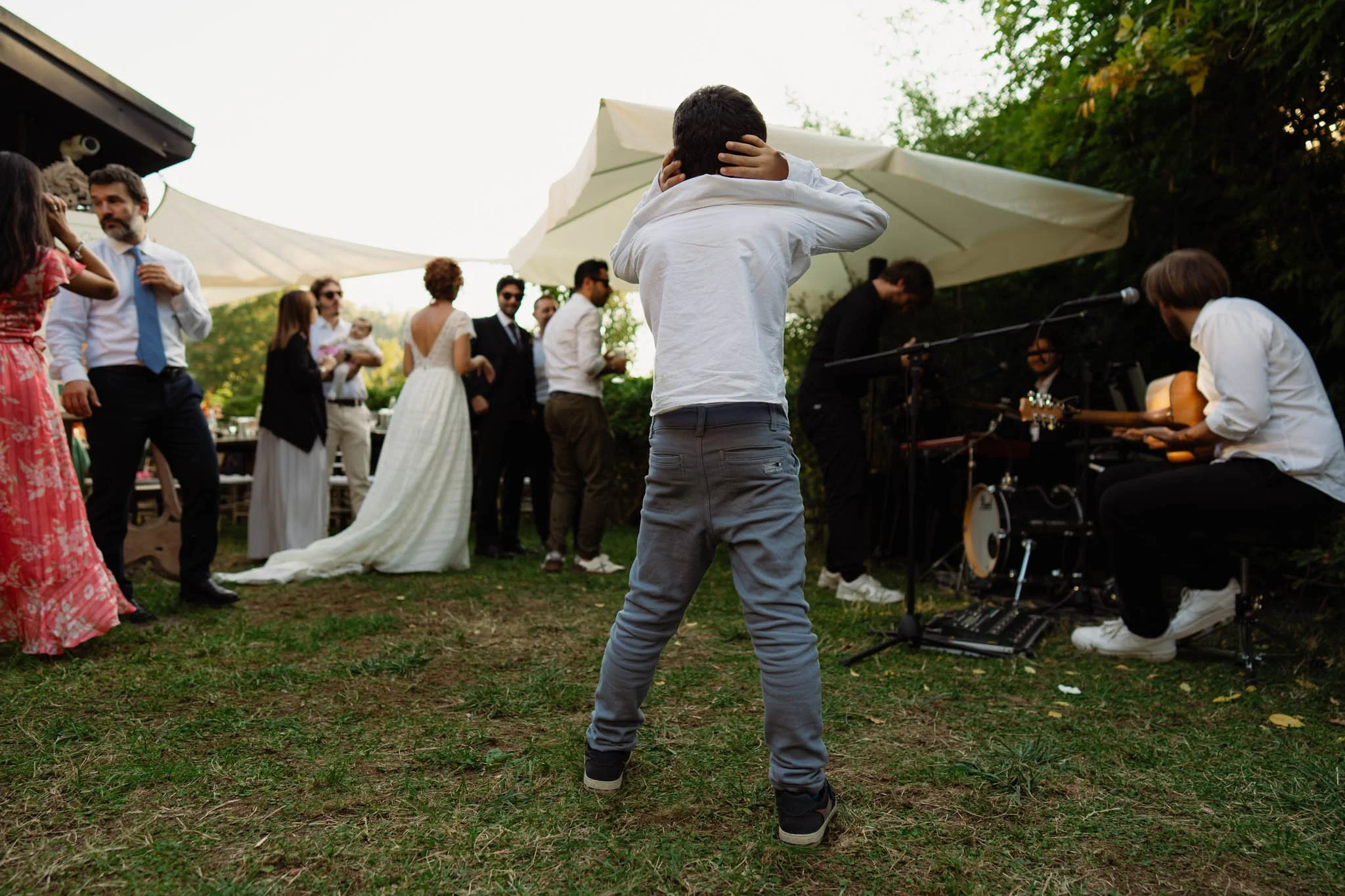 Una scena di una festa di matrimonio all'aperto con persone che ballano e musica dal vivo.