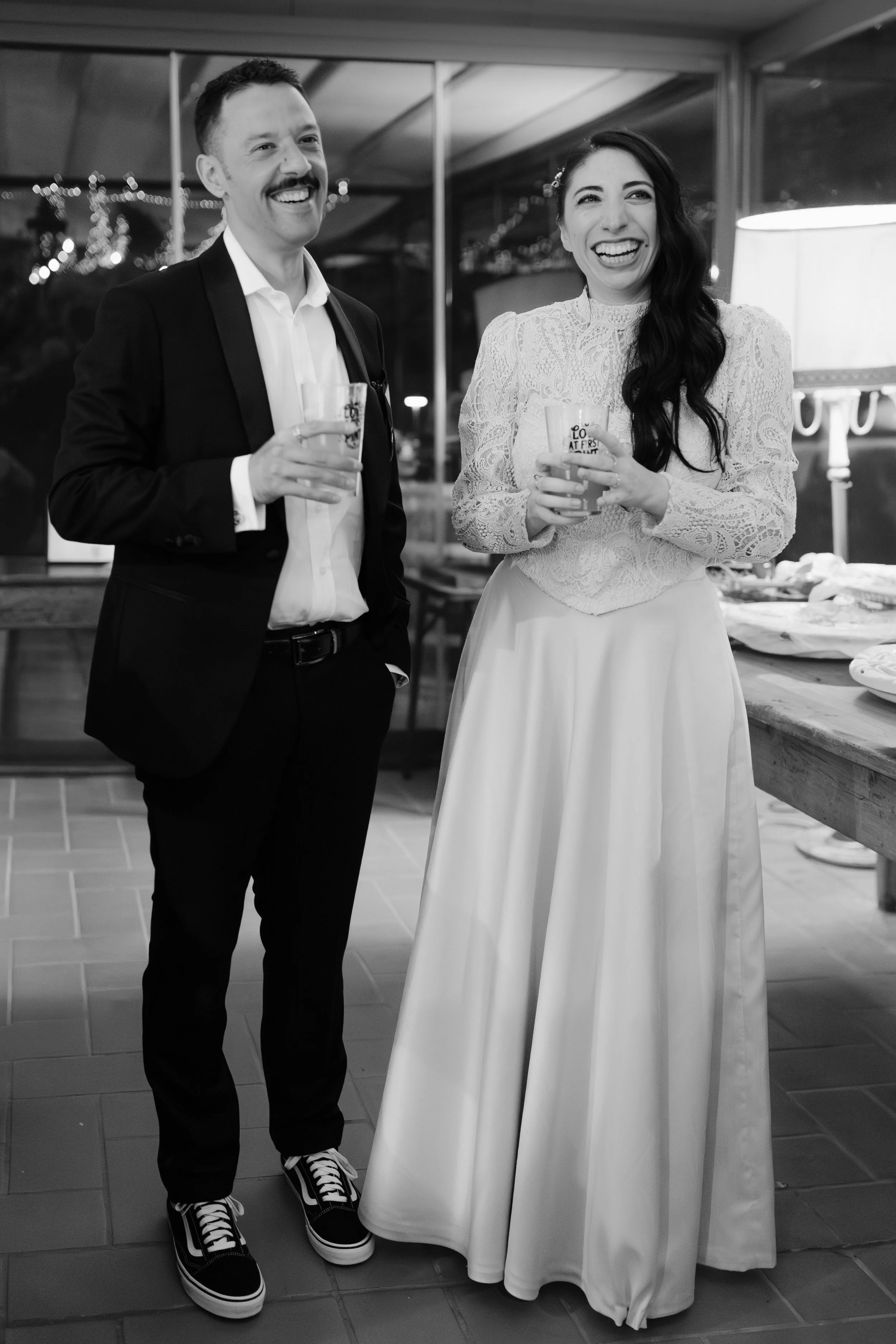 Una coppia di sposi vestiti in modo alternativo durante la festa di matrimonio, in bianco e nero.