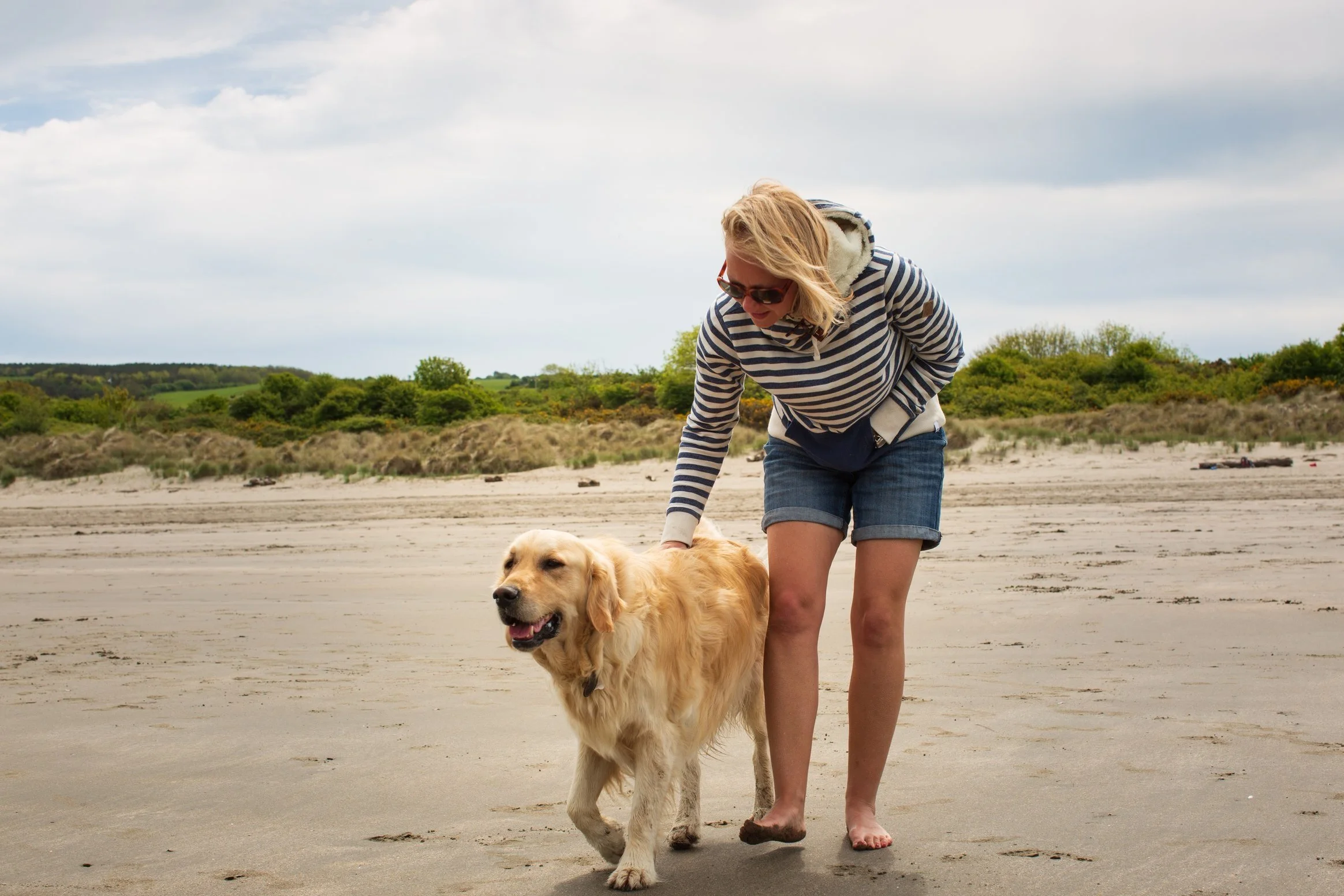photo of Helen Langdon on a beach in the summer with a golden retriever dog