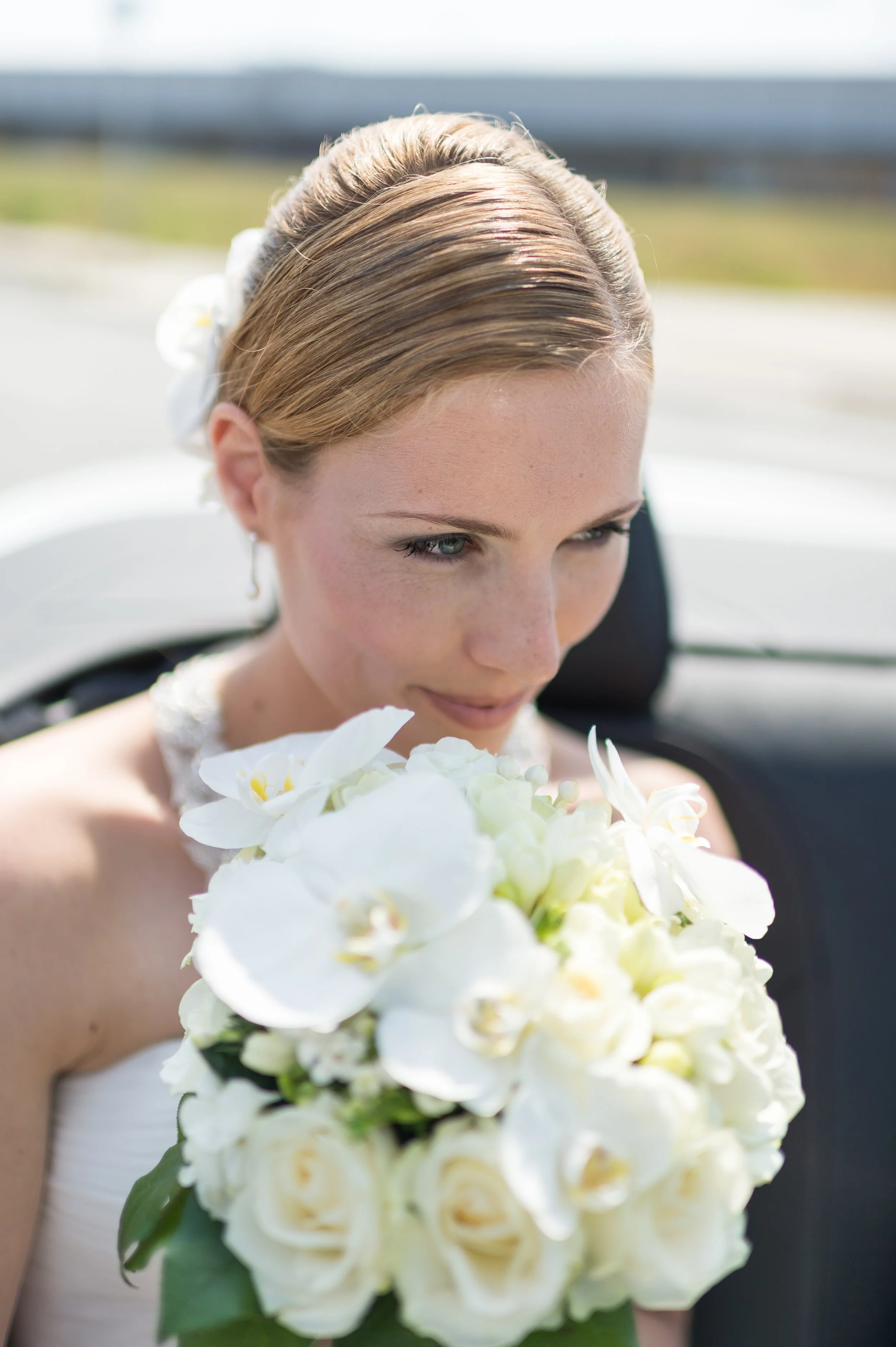 Junge Frau mit Brautkleid hält einen großen Brautstrauß aus weißen Blumen.