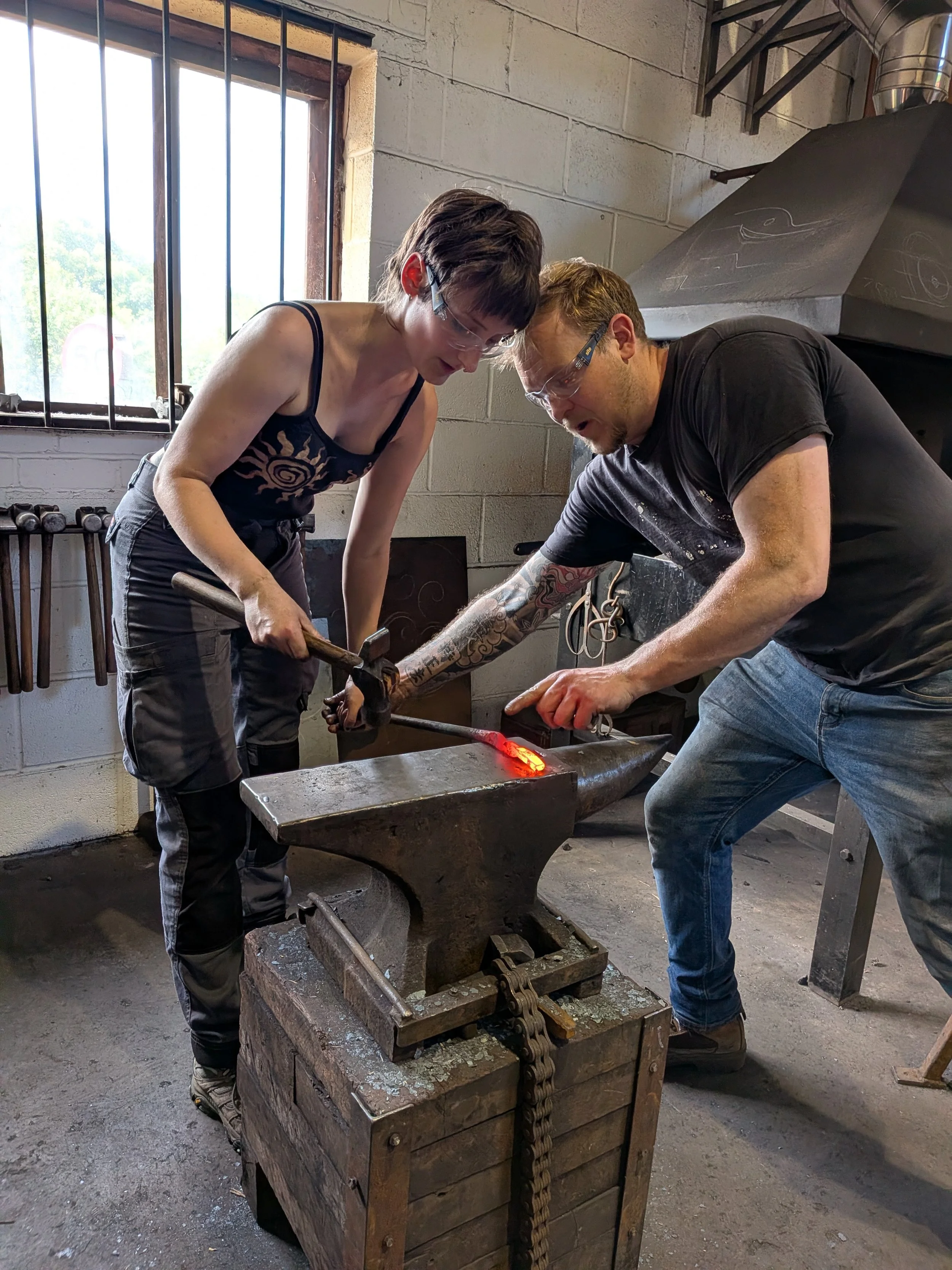 A blacksmith teaching a student on a 1-2-1 course how to make a pair of tongs