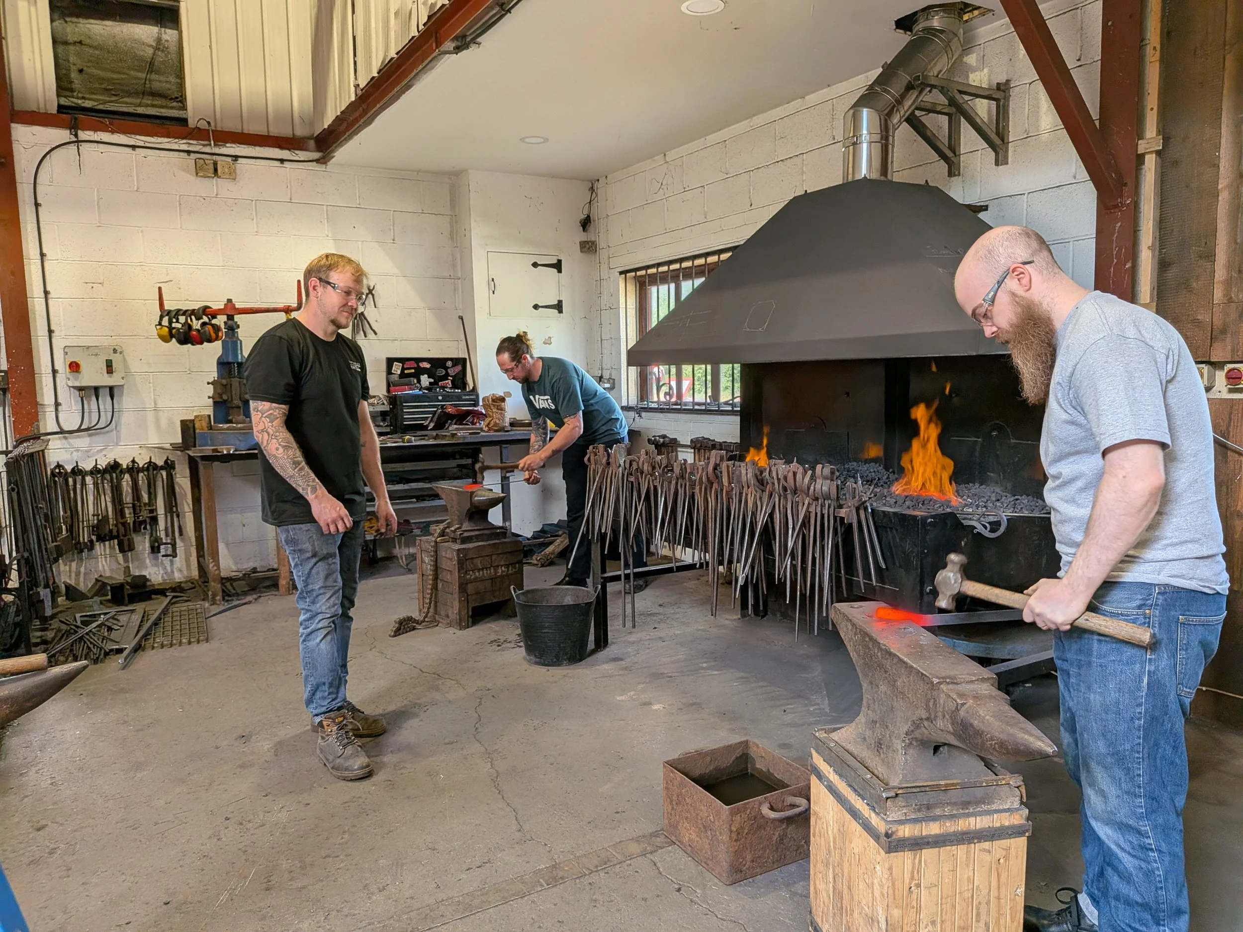 A blacksmith tutor watches his students working on the step that he has recently demonstrated to them.