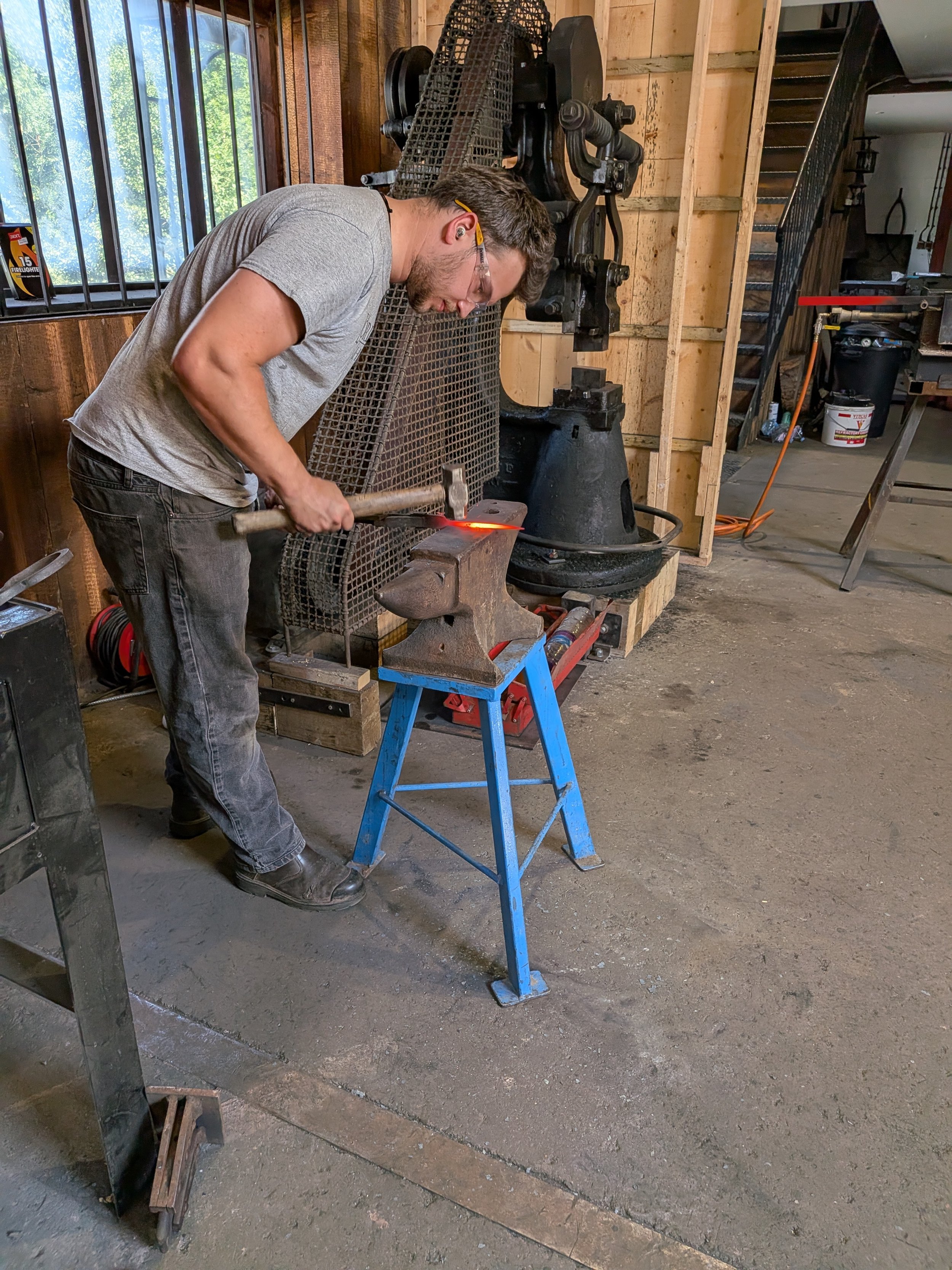 A blacksmith hammering a hot piece of steel on an anvil.