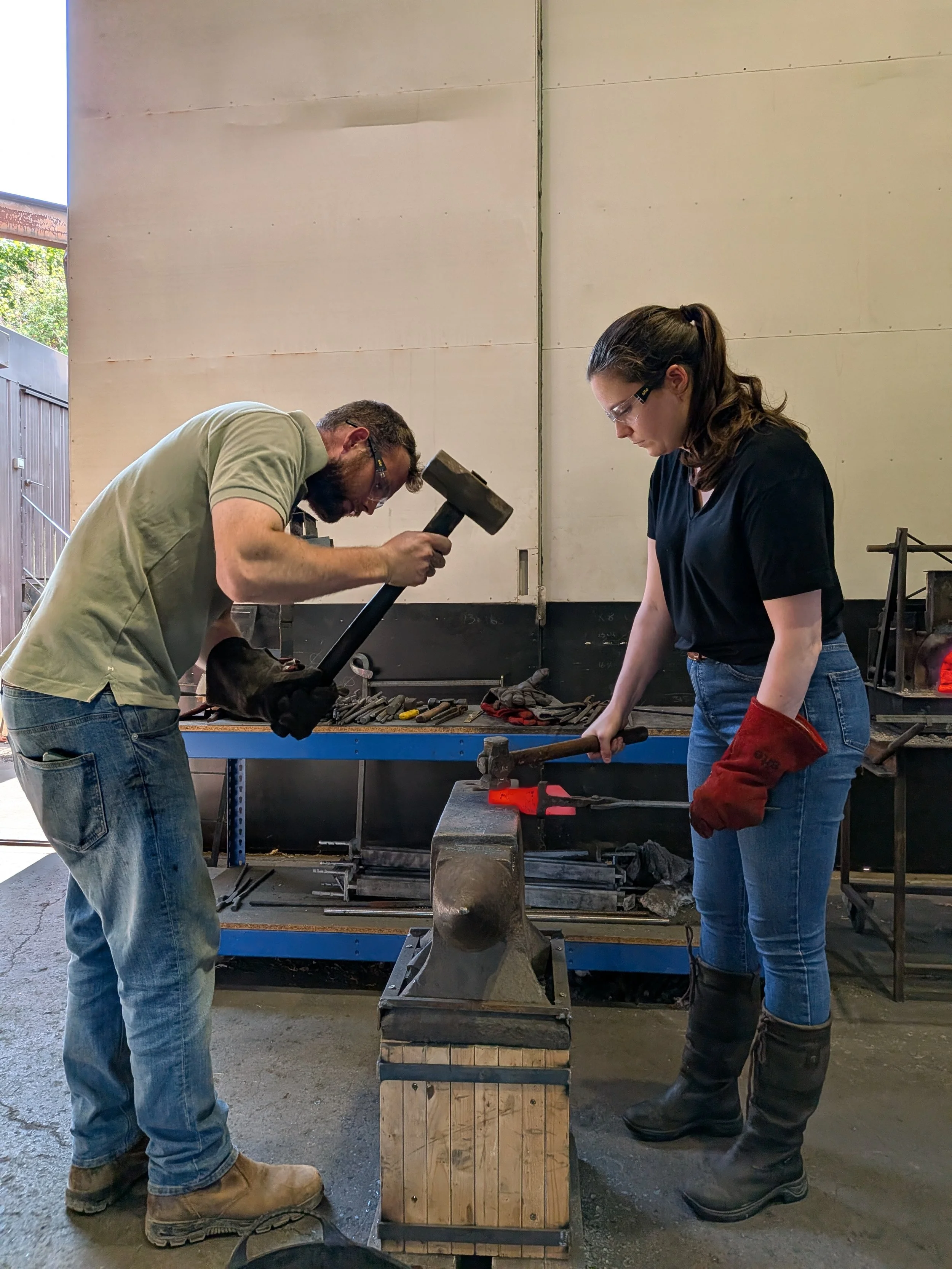 Blacksmith students, smith and striking to forge the tang of a knife.