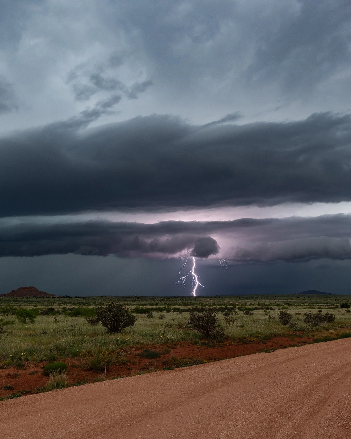 Magic in New Mexico, June 4th 2025.
.
I was riding between two severe thunderstorms, trying to stay ahead of the one behind me without running into the one in front. Spotted this ranch road with red dirt and green grass, so I quickly pulled off the m
