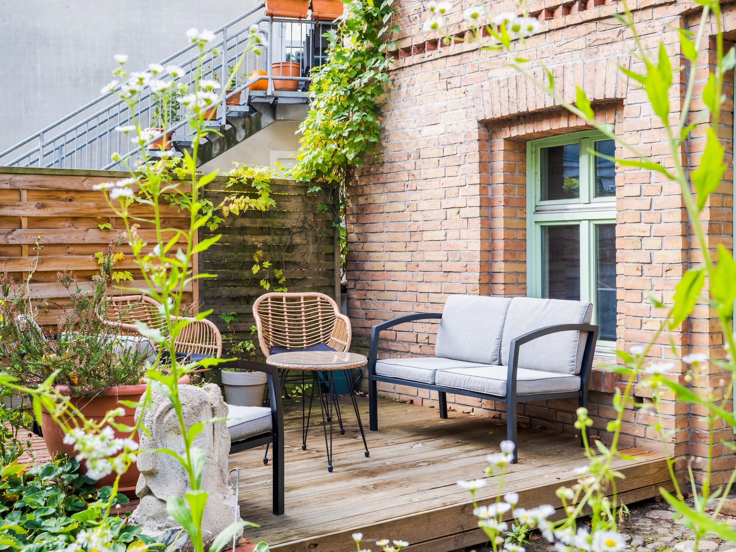 Gemütlicher Außenbereich der Neuen Remise mit Lounge-Möbeln, ideal für entspannte Pausen oder informelle Gespräche während Workshops. Der Bereich ist von Pflanzen umgeben und bietet eine ruhige, einladende Atmosphäre.