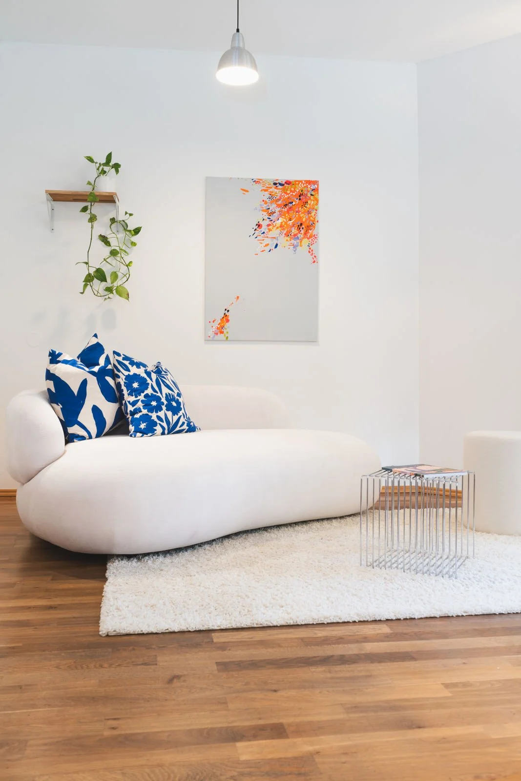 Moderne Besprechungsecke in der Neuen Remise mit einem eleganten Sofa, blauen Kissen und minimalistischer Dekoration. Der Raum bietet eine ruhige, einladende Atmosphäre für kreative Meetings und Workshops.