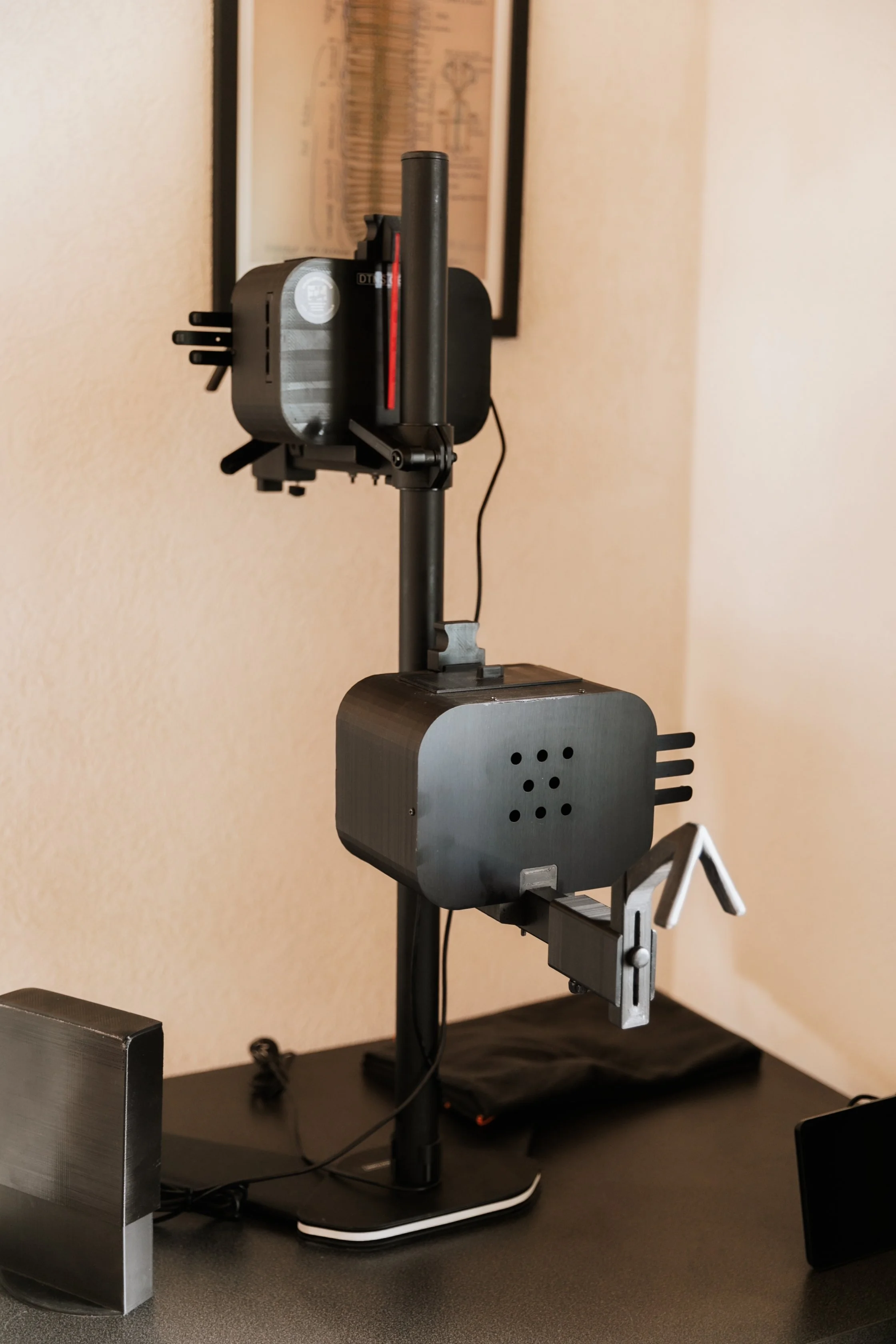 Un appareil de test automatisé avec des bras mécaniques, fixé sur une table, utilisé pour la calibration ou la maintenance technologique.