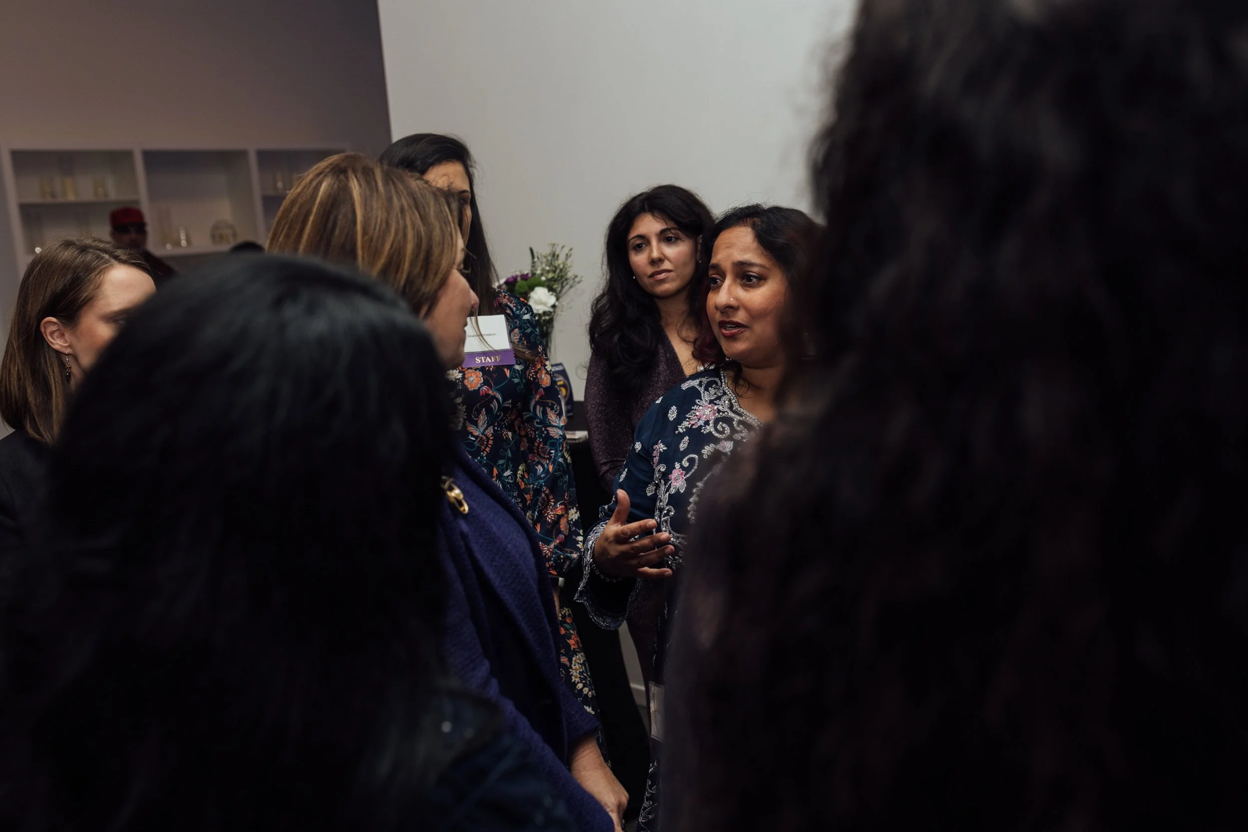 Group of women engaged in conversation at an indoor event.