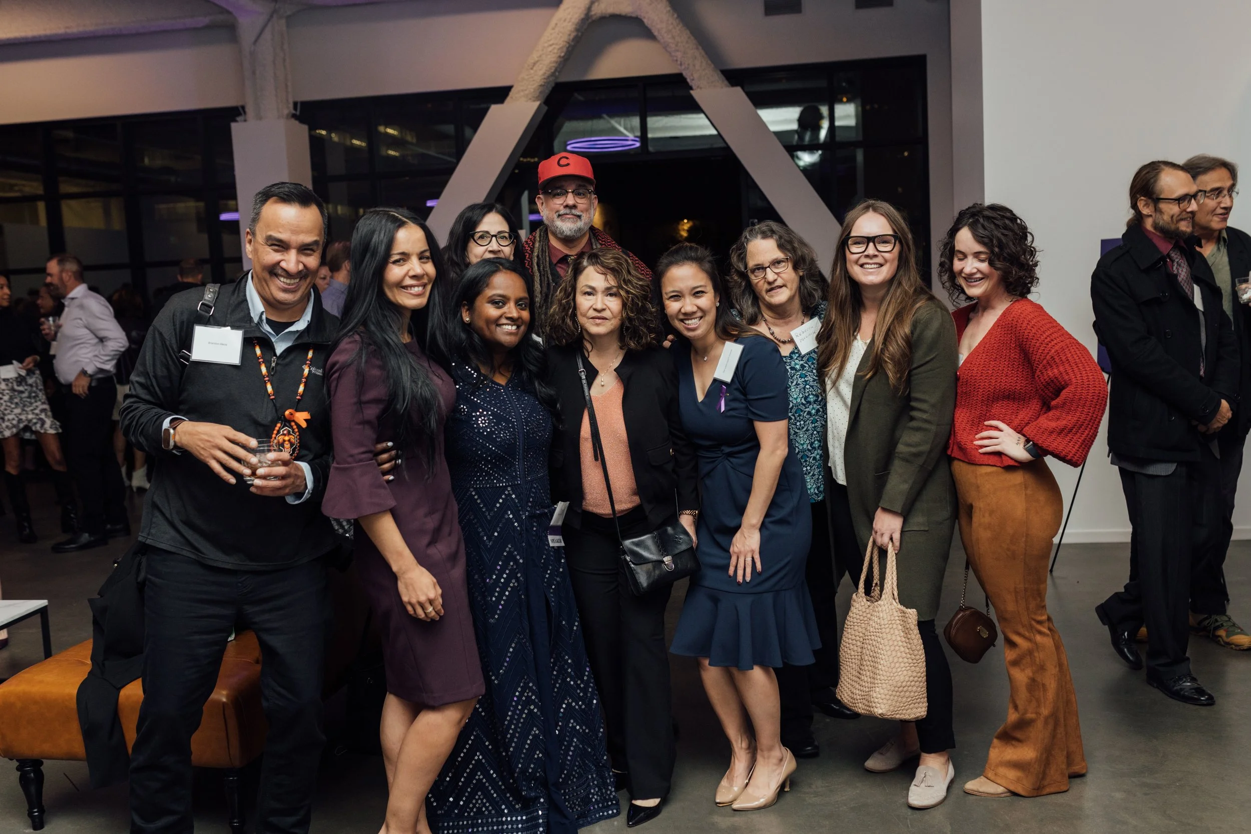 A group of diverse people standing together at an indoor event, smiling for the camera.