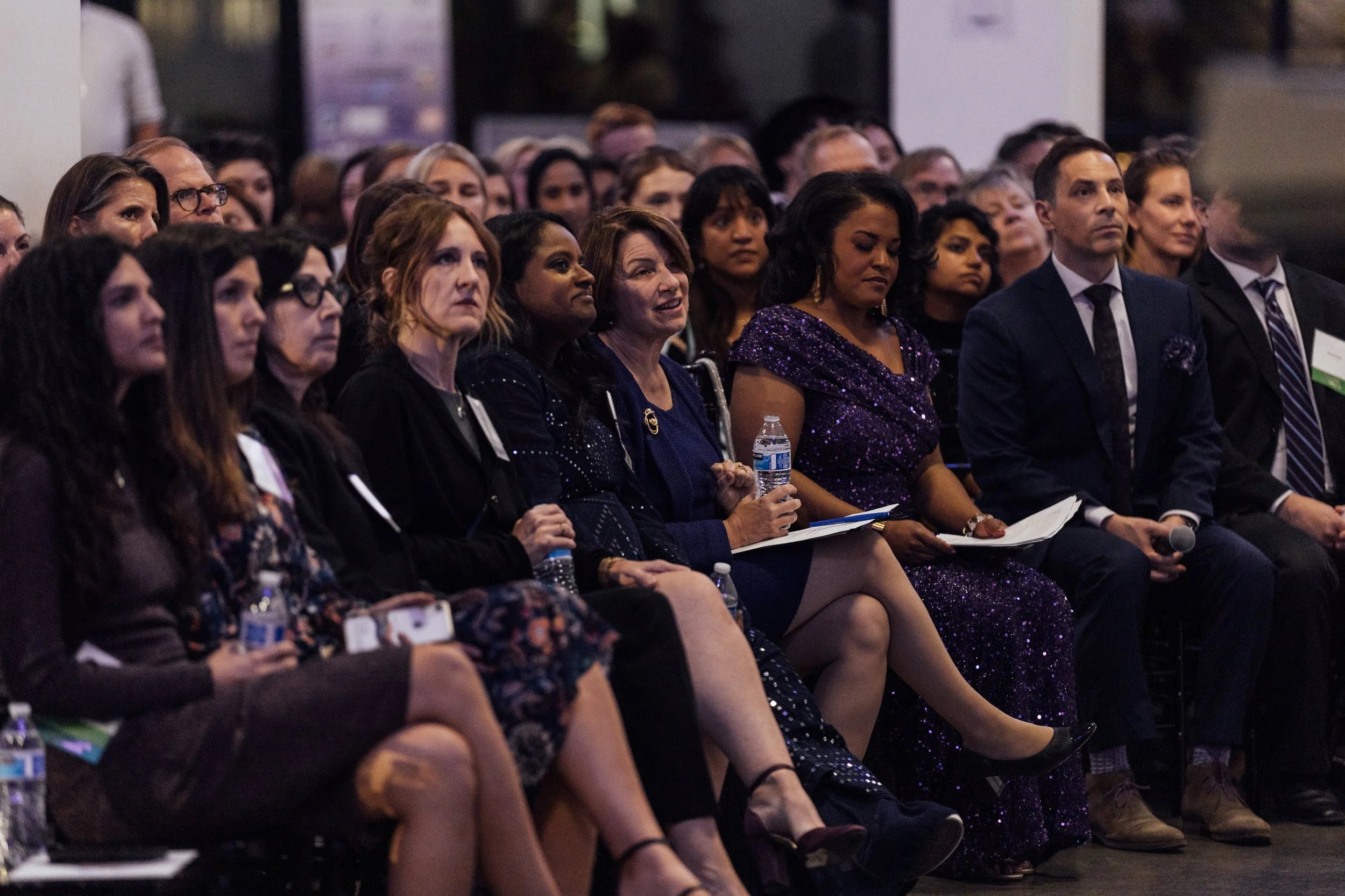 Group of men and women seated closely together, attentively listening at a professional conference or seminar.
