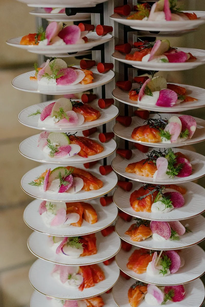 Multiple plates with smoked salmon, radish slices, and garnishes on a multi-tiered serving stand.