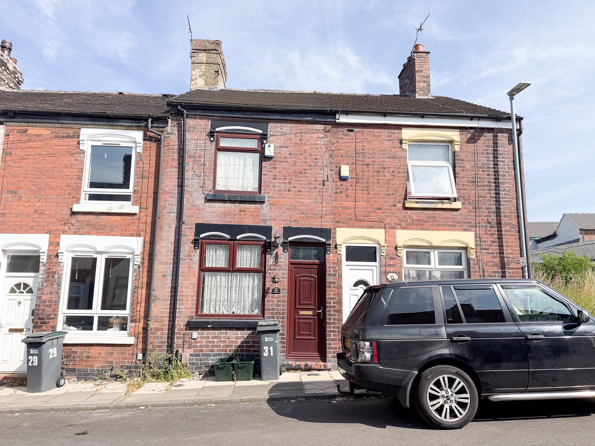 Front elevation of a traditional two-bedroom Victorian mid-terrace house on Hillary Street, Cobridge, with red brick façade, bay-style front window, and on-street parking.