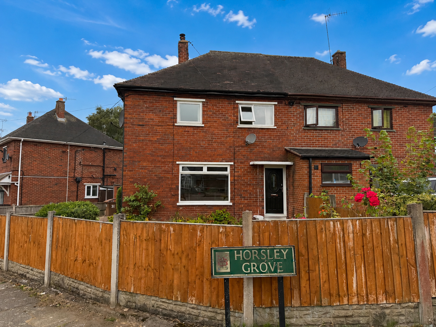 Front elevation of a well-presented three-bedroom semi-detached house on Horsley Grove, Blurton, occupying a generous corner plot with a driveway, enclosed gardens and a bright blue sky.