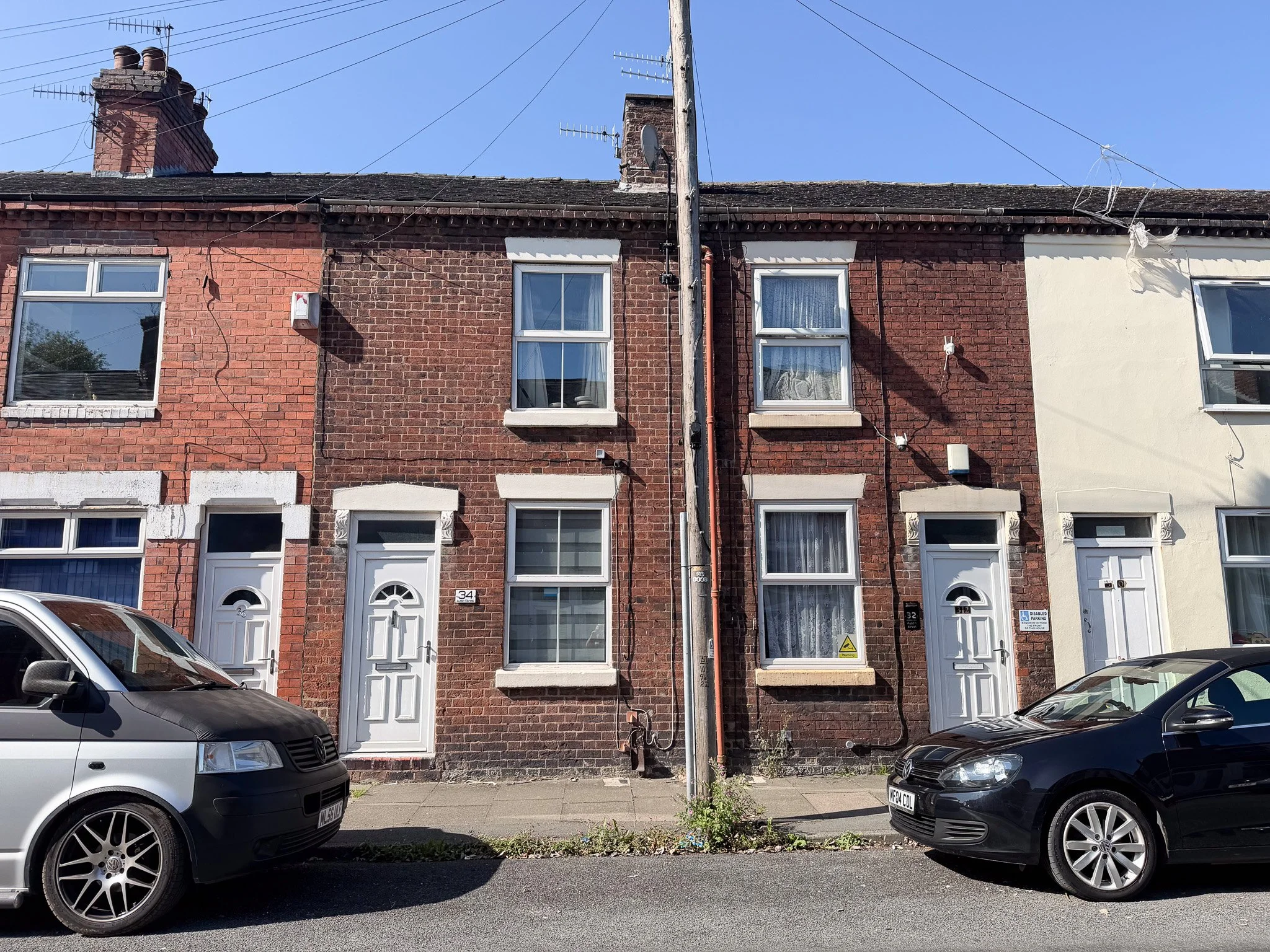 Front exterior of a three-storey Victorian terraced house on Austin Street, Joiners Square, Stoke-on-Trent, with traditional red brick frontage and white uPVC windows and entrance door.