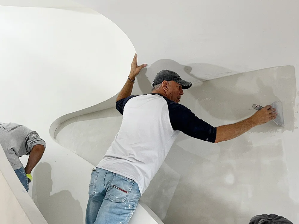 Artisan skim-coating a stair wall