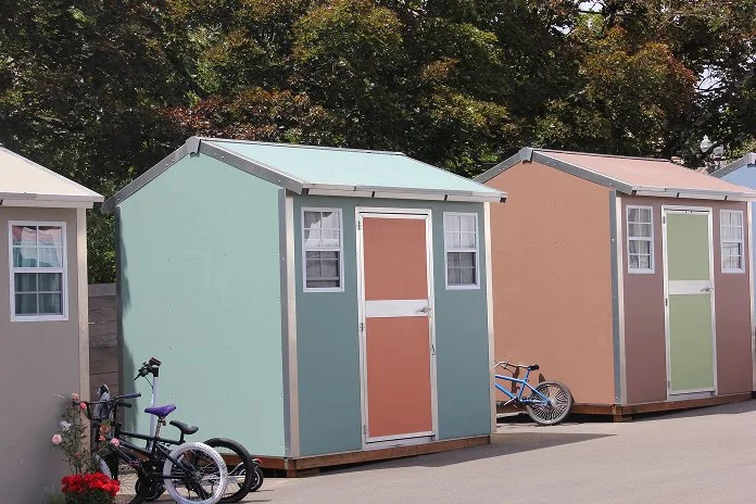 Colorful safe stay units with bicycles parked nearby, set against a background of green trees.