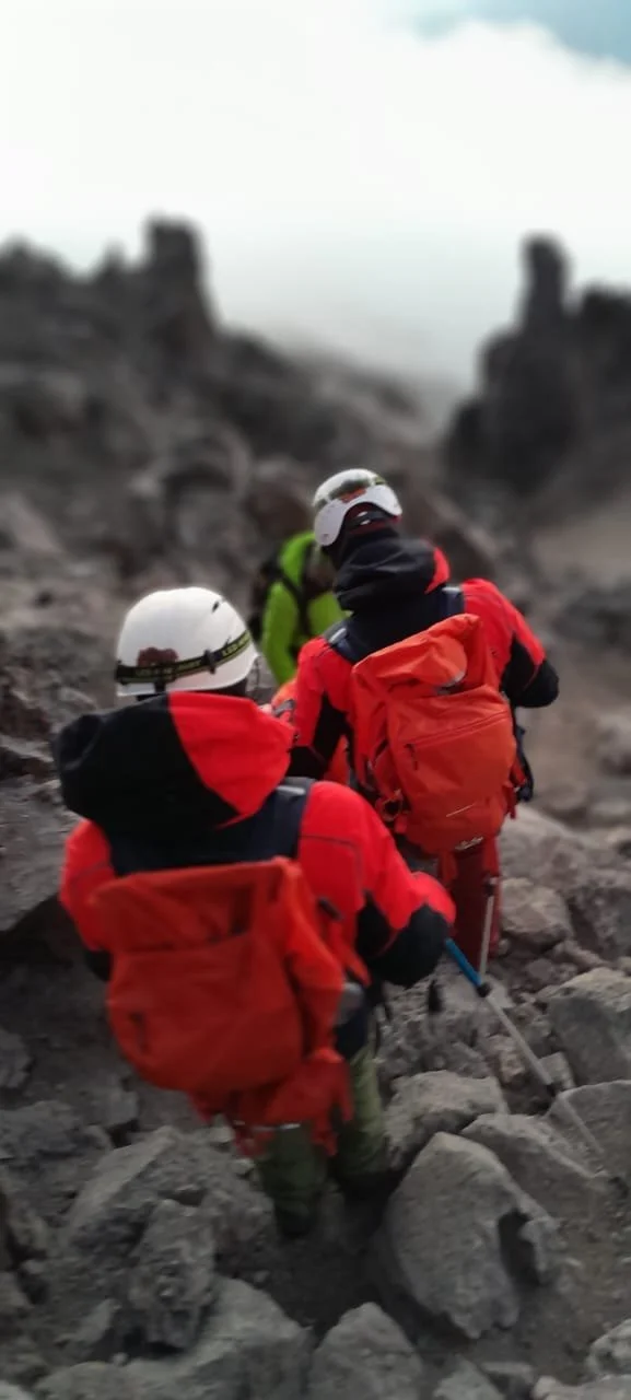 Tres montañistas con equipo de escalada avanzando por terrenos rocosos
