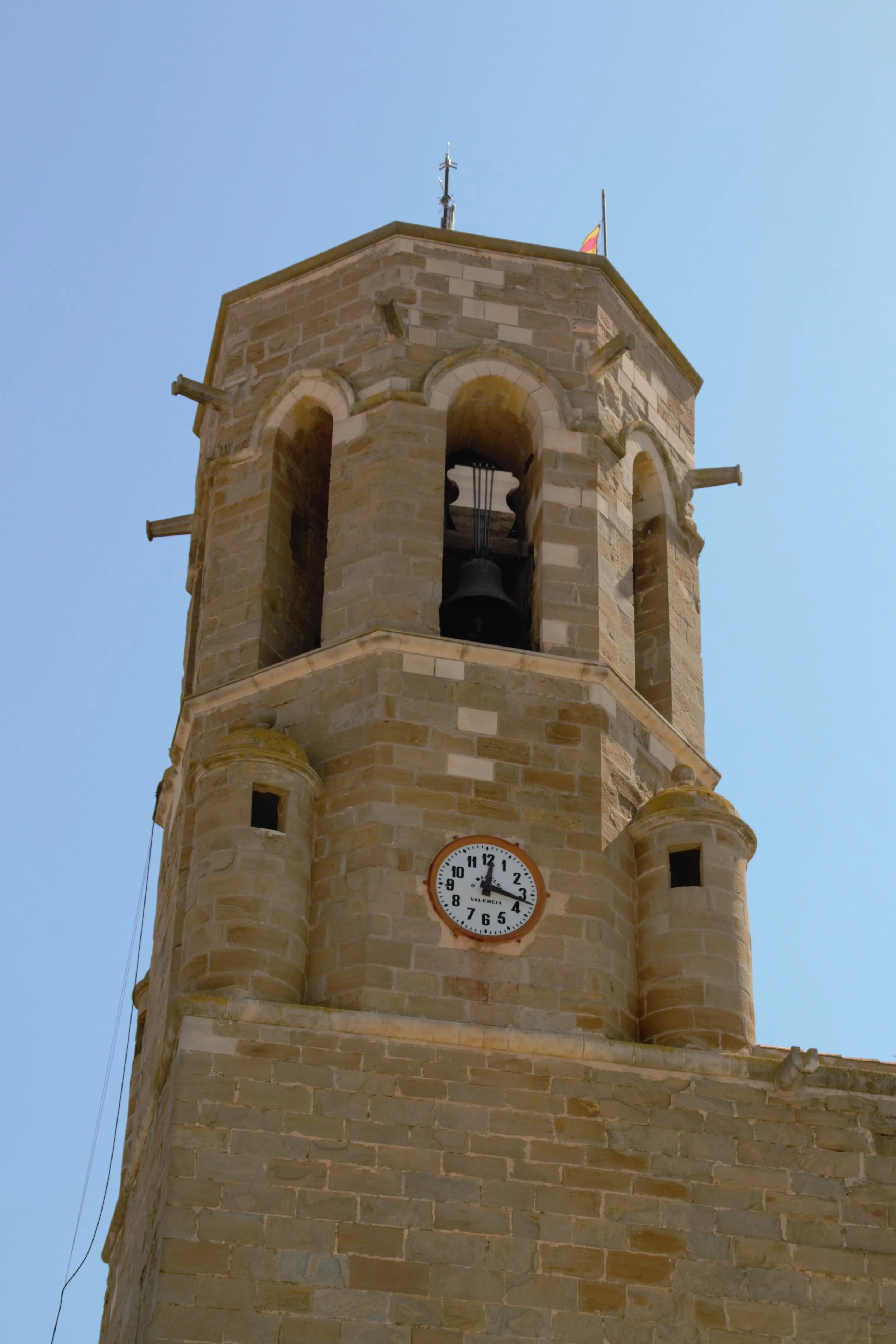 Campanar de Santa Maria de Linyola amb el rellotge i les campanes sota el cel blau.
