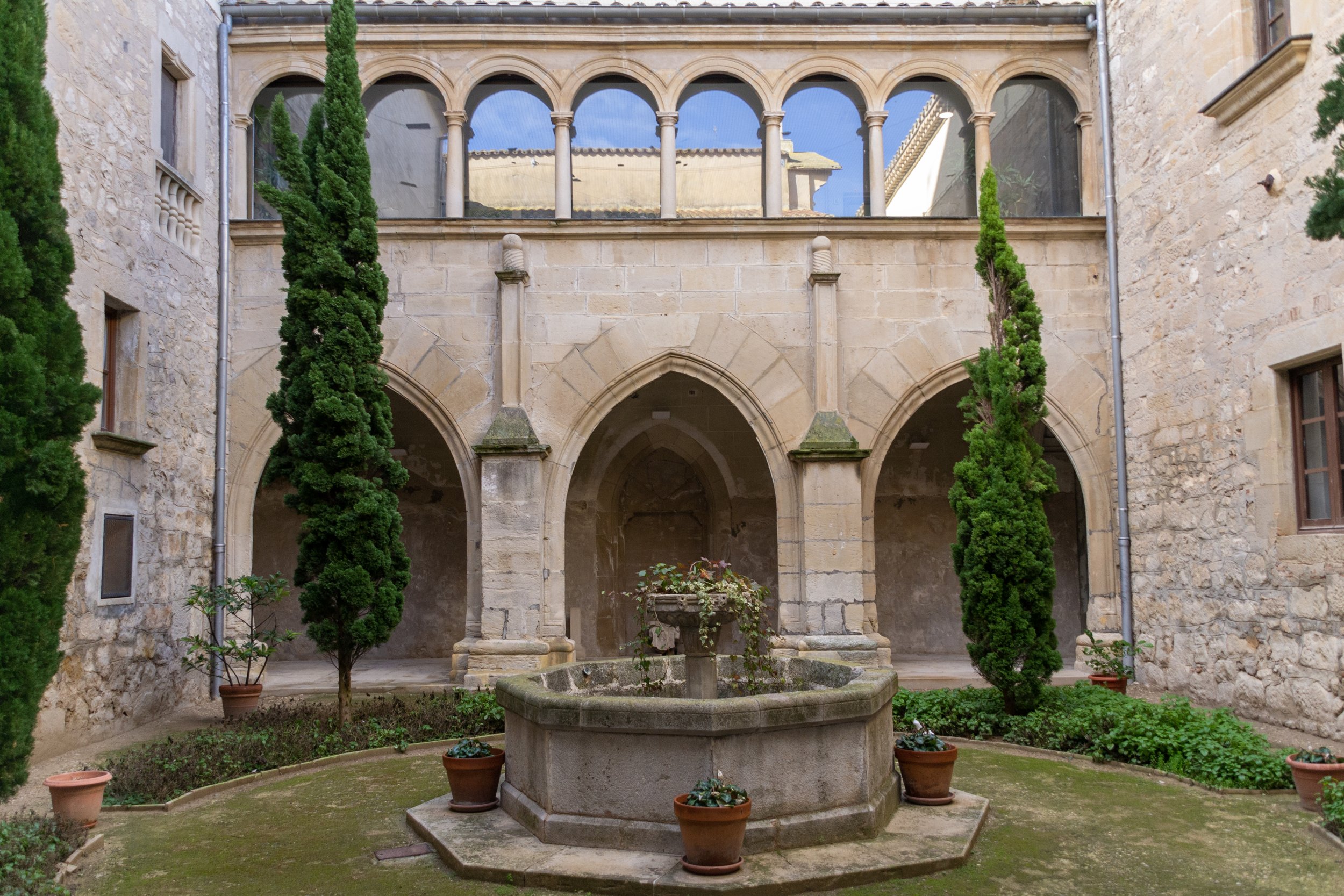 Claustre del Convent de Sant Bartomeu de Bellpuig amb arcs, xiprers i font central.