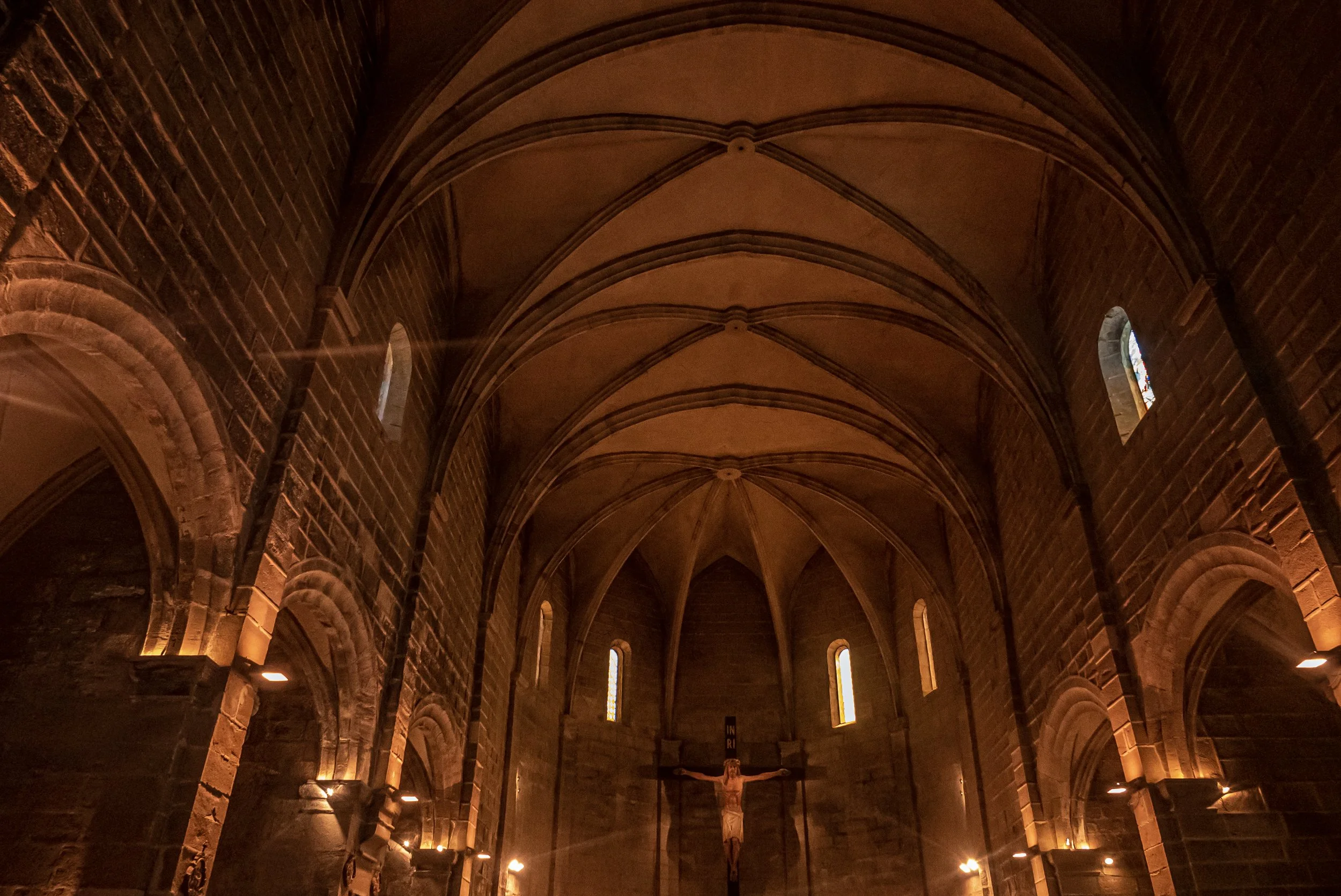 Interior de Santa Maria de Linyola amb voltes de pedra i el Crist al fons.