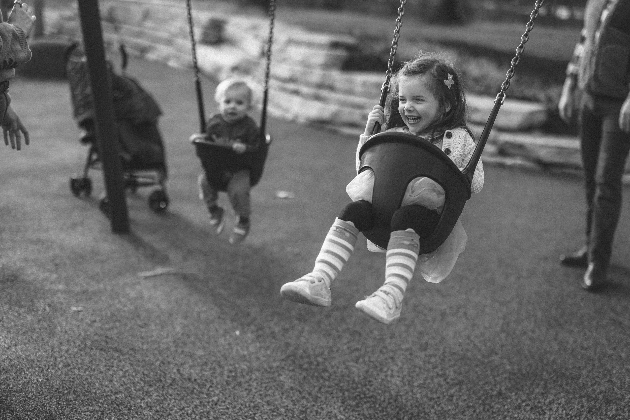 A giggling toddler swinging a local park.