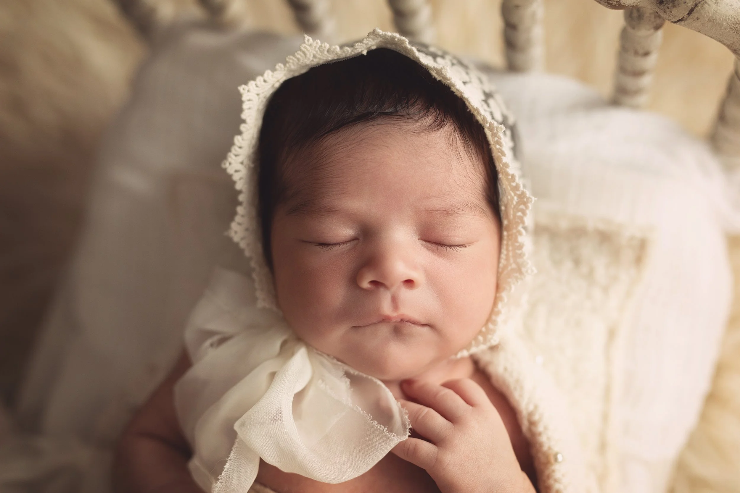 Newborn sleeping with cream lace bonnet in rustic spindle bed from hello little props.