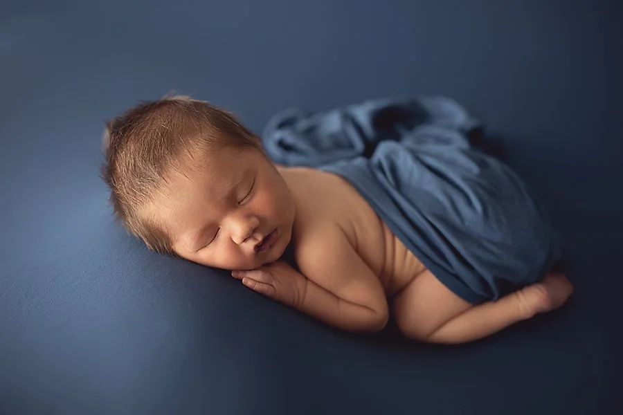 newborn baby boy sleeping on blue fabric in soft natural light in greencastle pa newborn photography studio