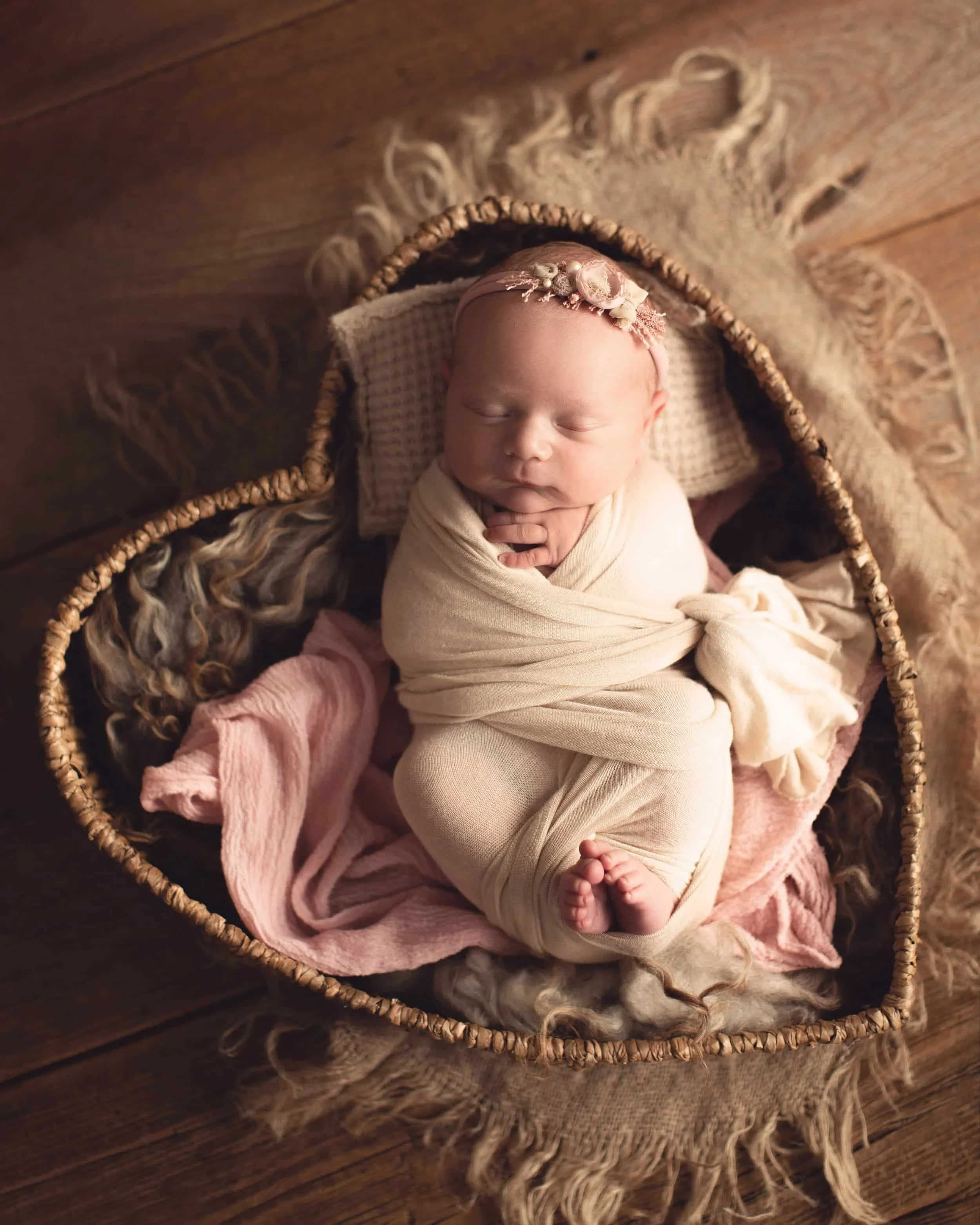 moody newborn photography image of a newborn in a heart basket with pink accents