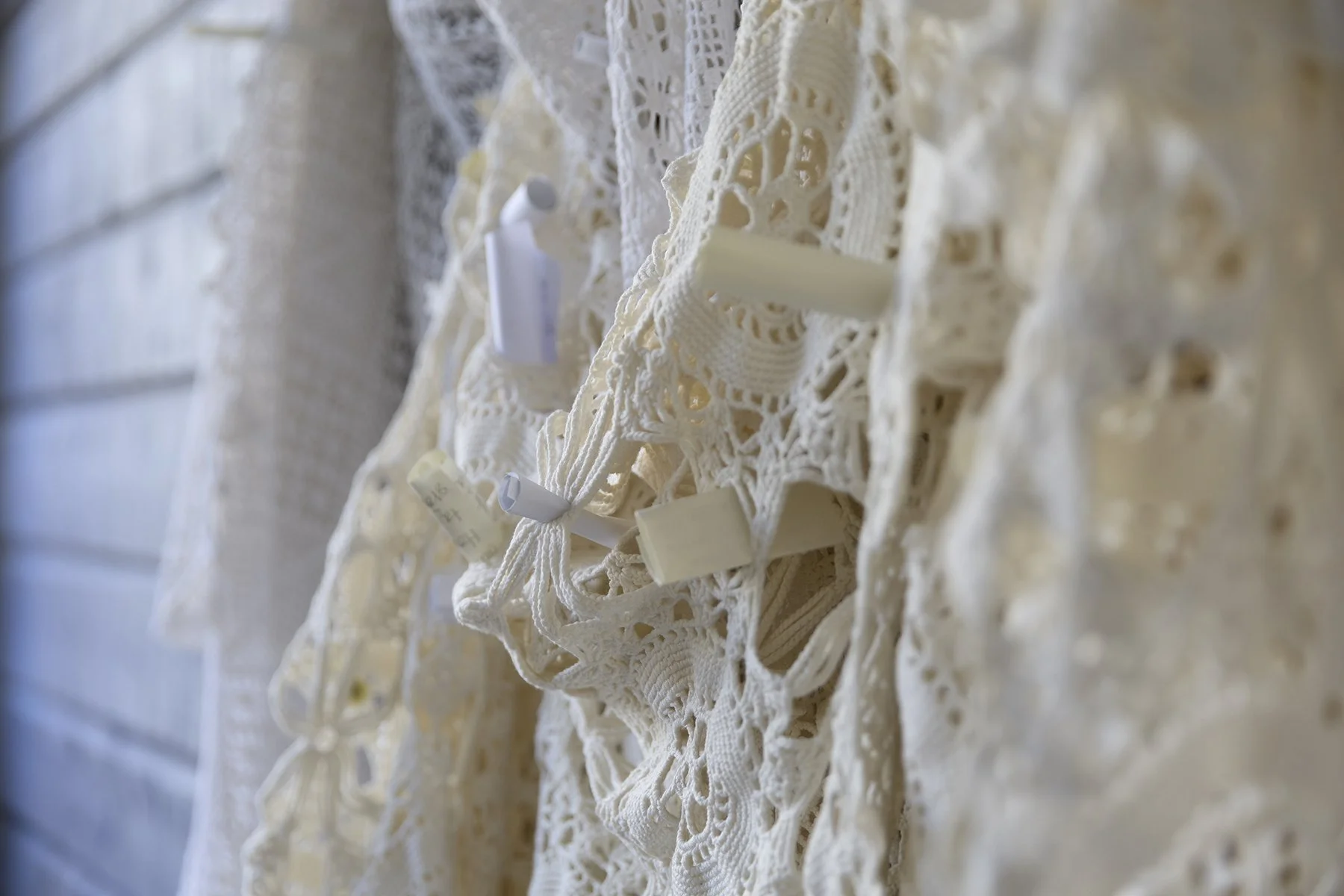 Alla vi maskor. Närbild på hälsningar instuckna bland öglorna. Hälsningarna samlas in, dokumenteras och sorteras, för att bli del i framtida verk. © Karin Lönnå. (Foto: Kristofer Lönnå.) 