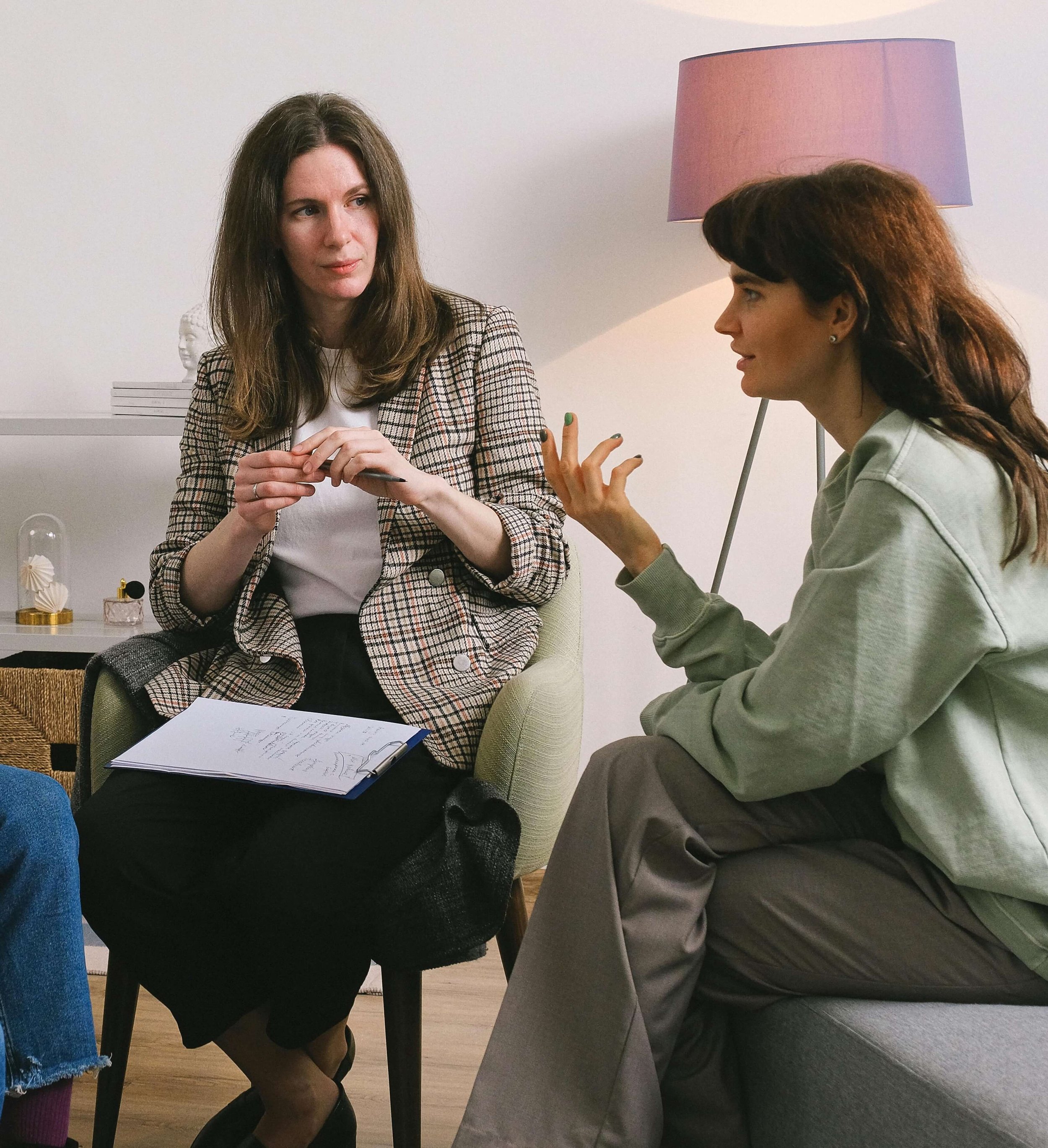 Two women in professional conversation during therapy session. Through Christian counseling in Tampa, FL, you'll find compassionate support that honors both your mental health and spiritual journey.