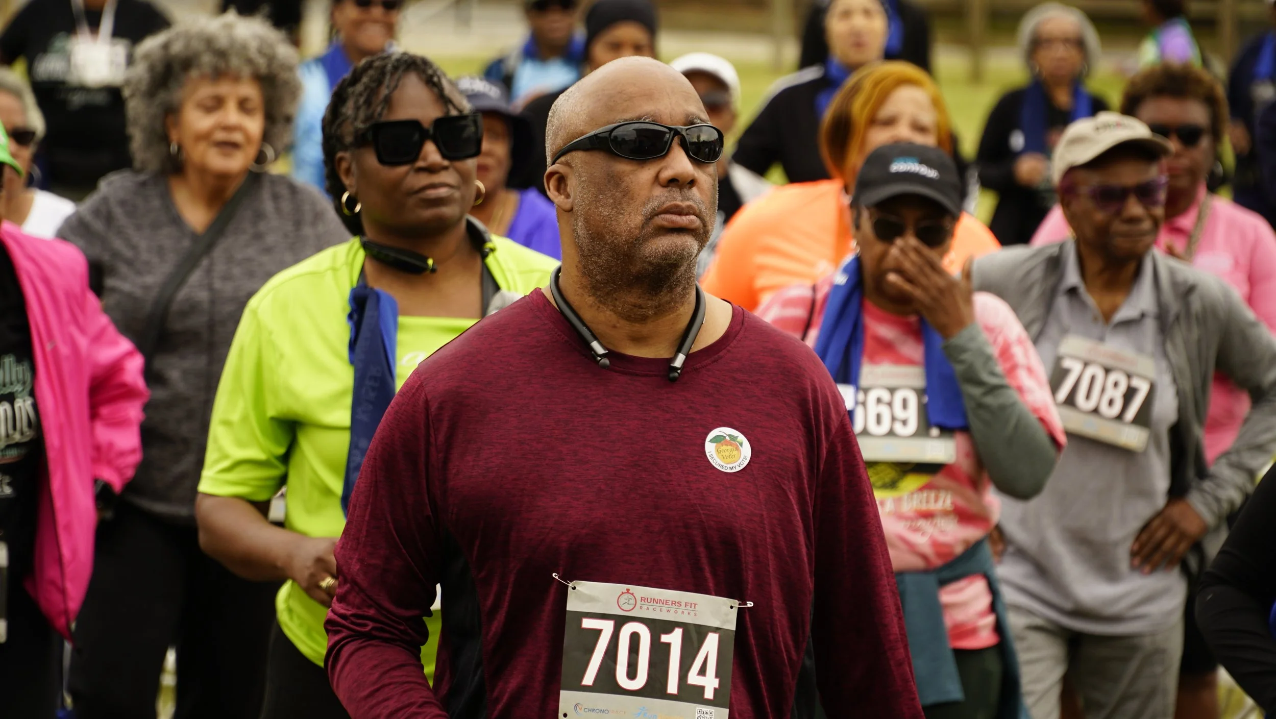A group of diverse people exercising in a field for a walking race.