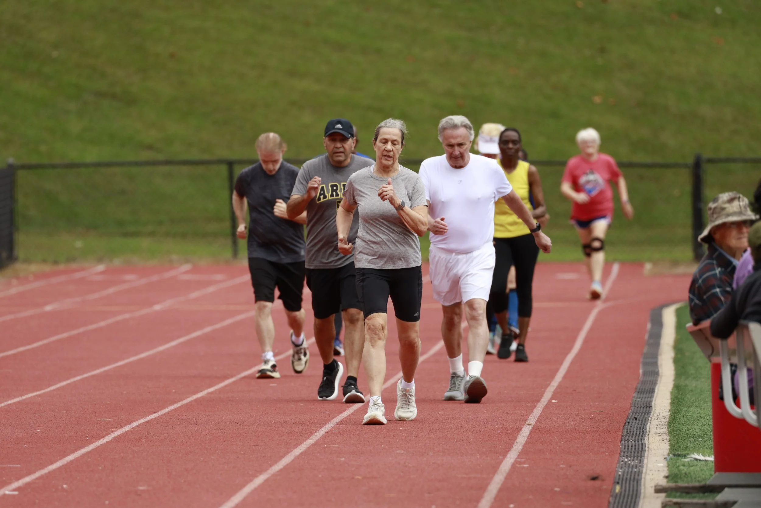 A group of diverse people exercising in a field for a walking race.