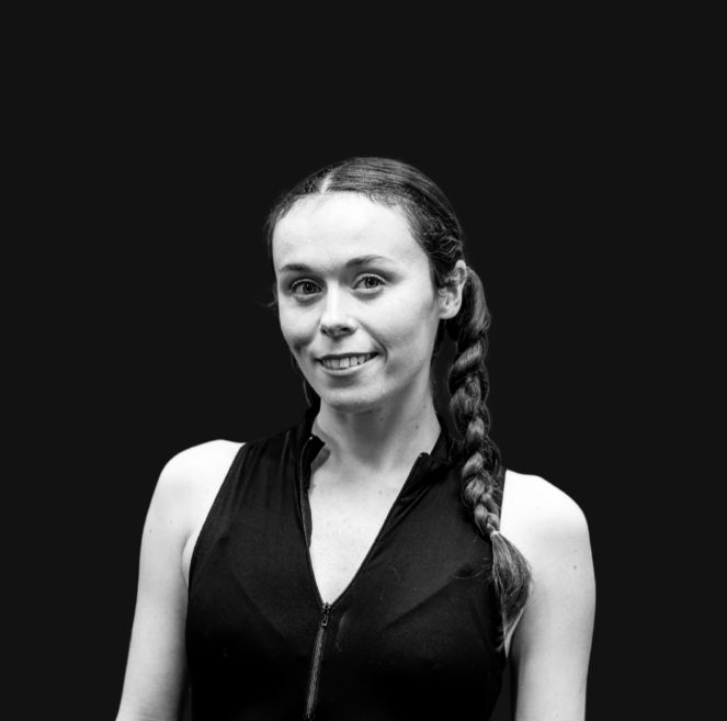 Young woman with red hair styled in braids, wearing a light blue vintage dress with white lace detailing on the collar and shoulders, standing against a neutral background.
