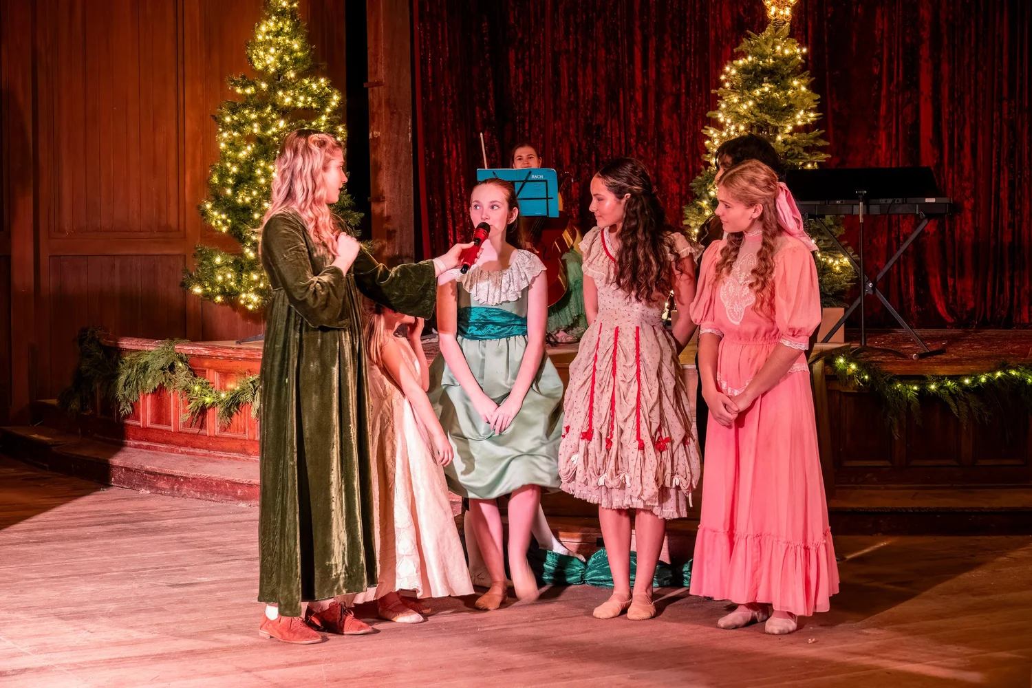 Performers on stage with Christmas trees behind them.