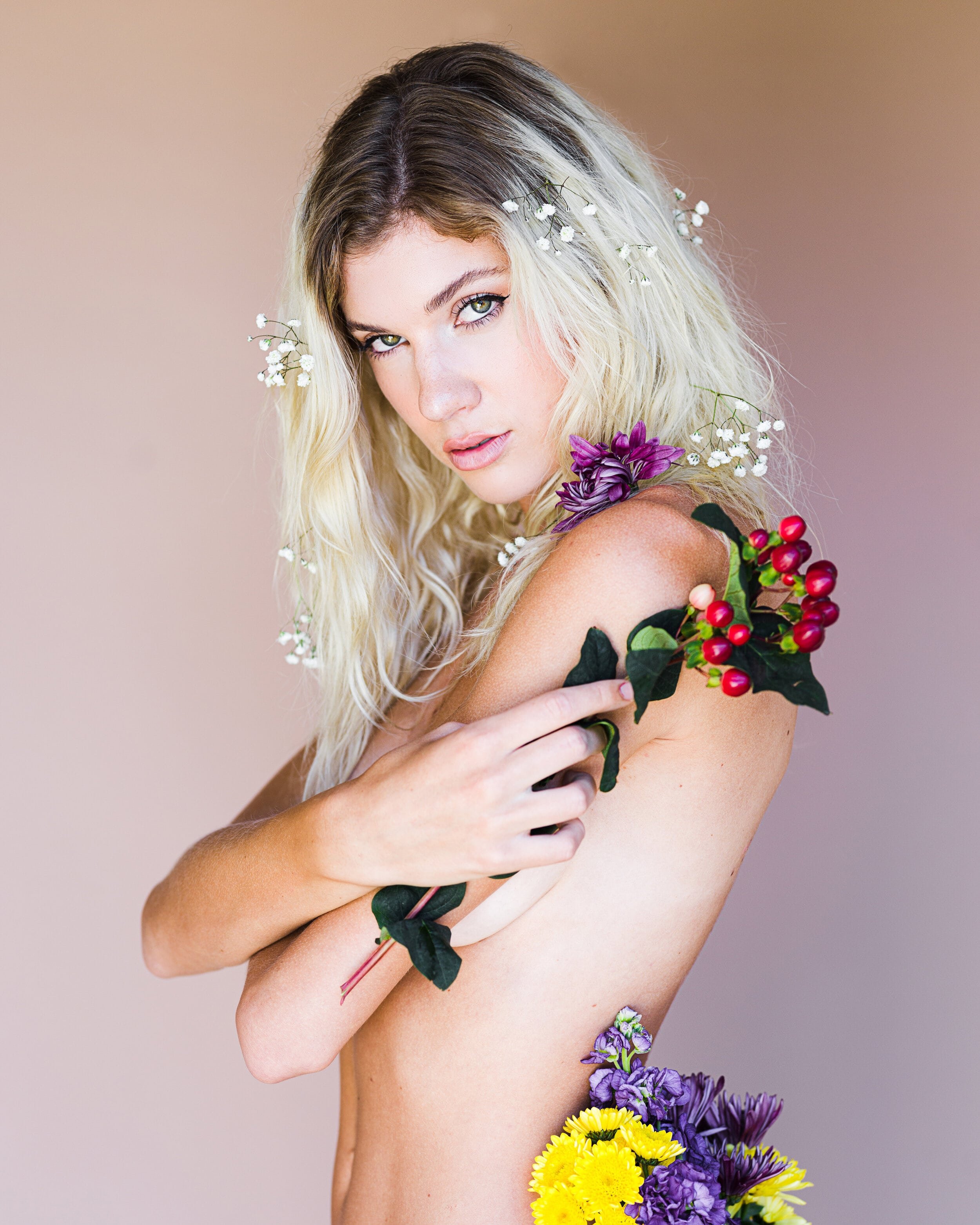 Floral creative portrait with blonde model holding various flowers