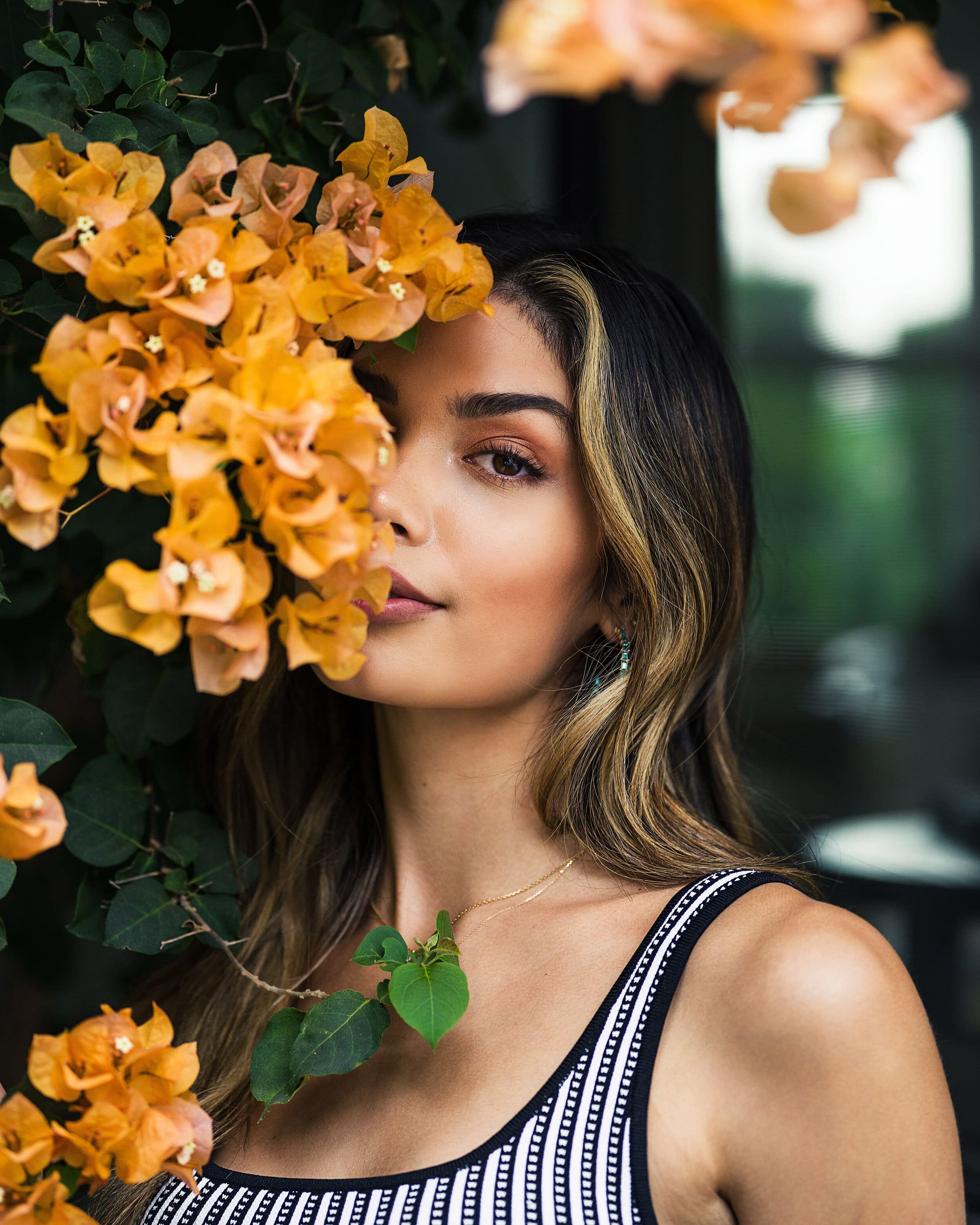 Floral creative portrait with model standing behind beautiful orange flowers
