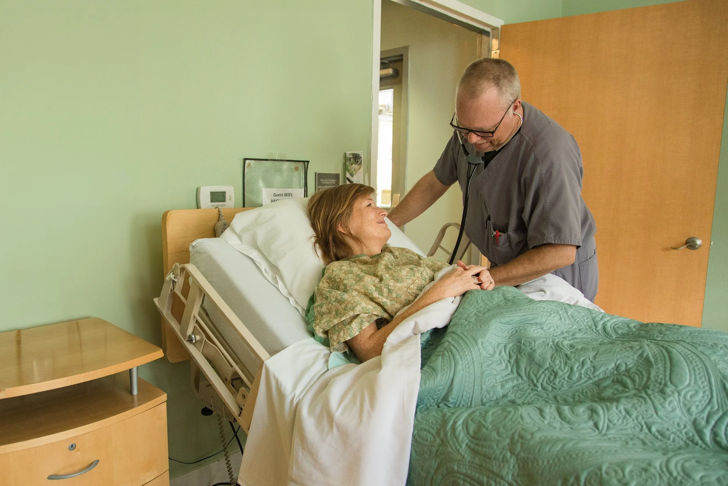 Healthcare professional comforting a patient in a hospice bed at Hospice Austin, symbolizing compassionate care.